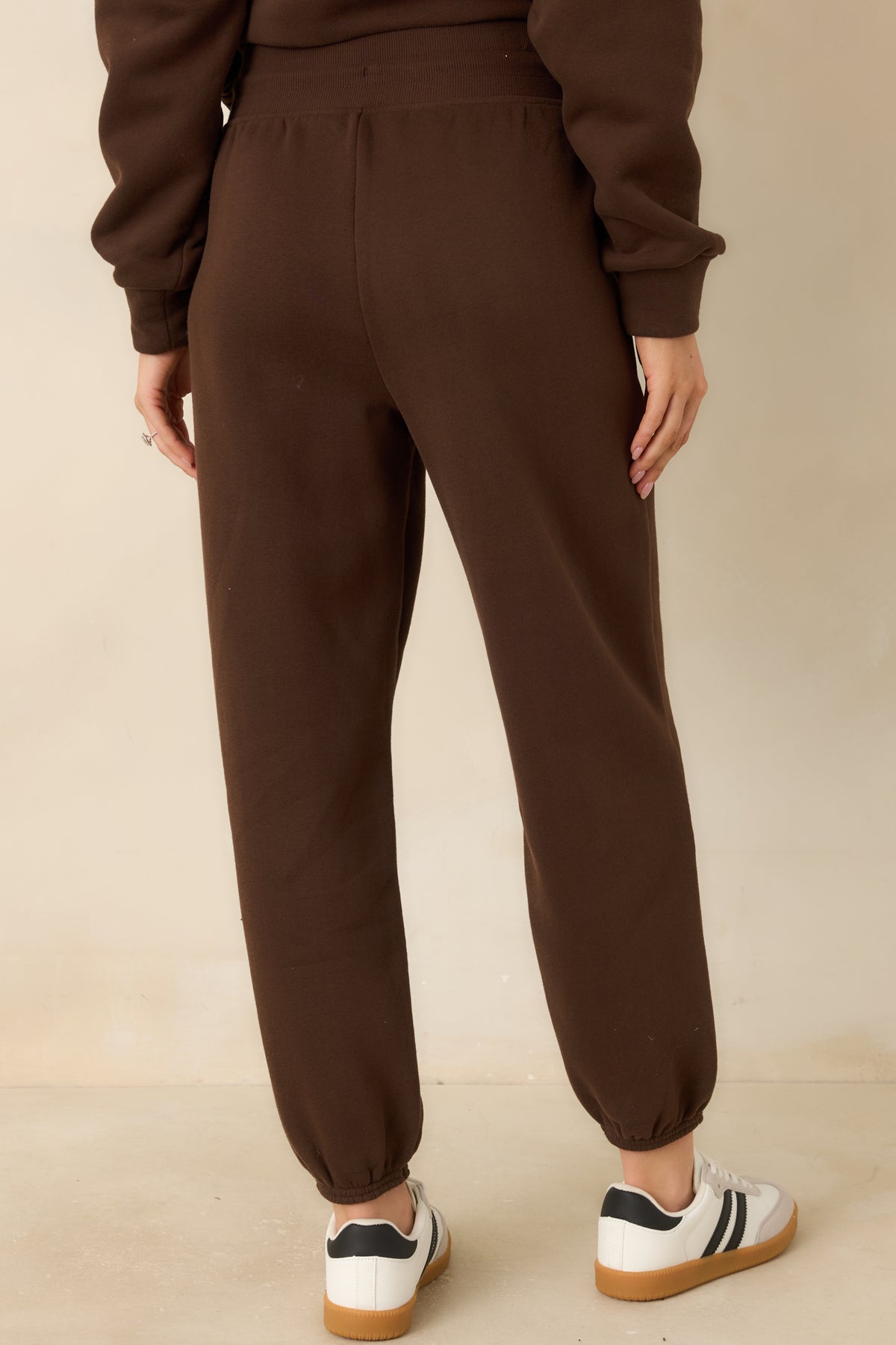 Rear of the brown fleece joggers, showing the smooth fabric and relaxed tapered-leg shape.
