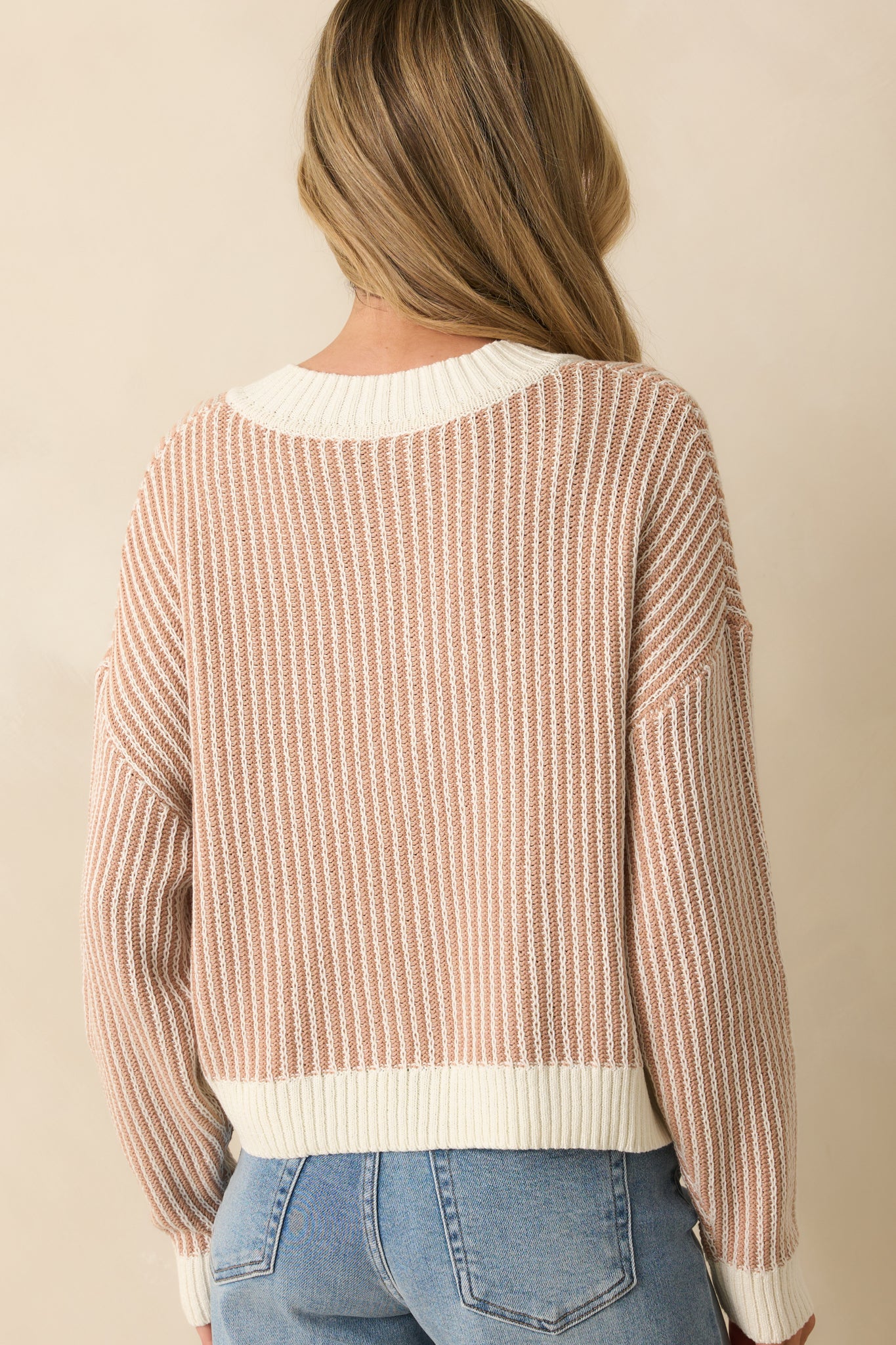 Rear view of camel brown and ivory striped sweater with ribbed hemline and relaxed knit fit.