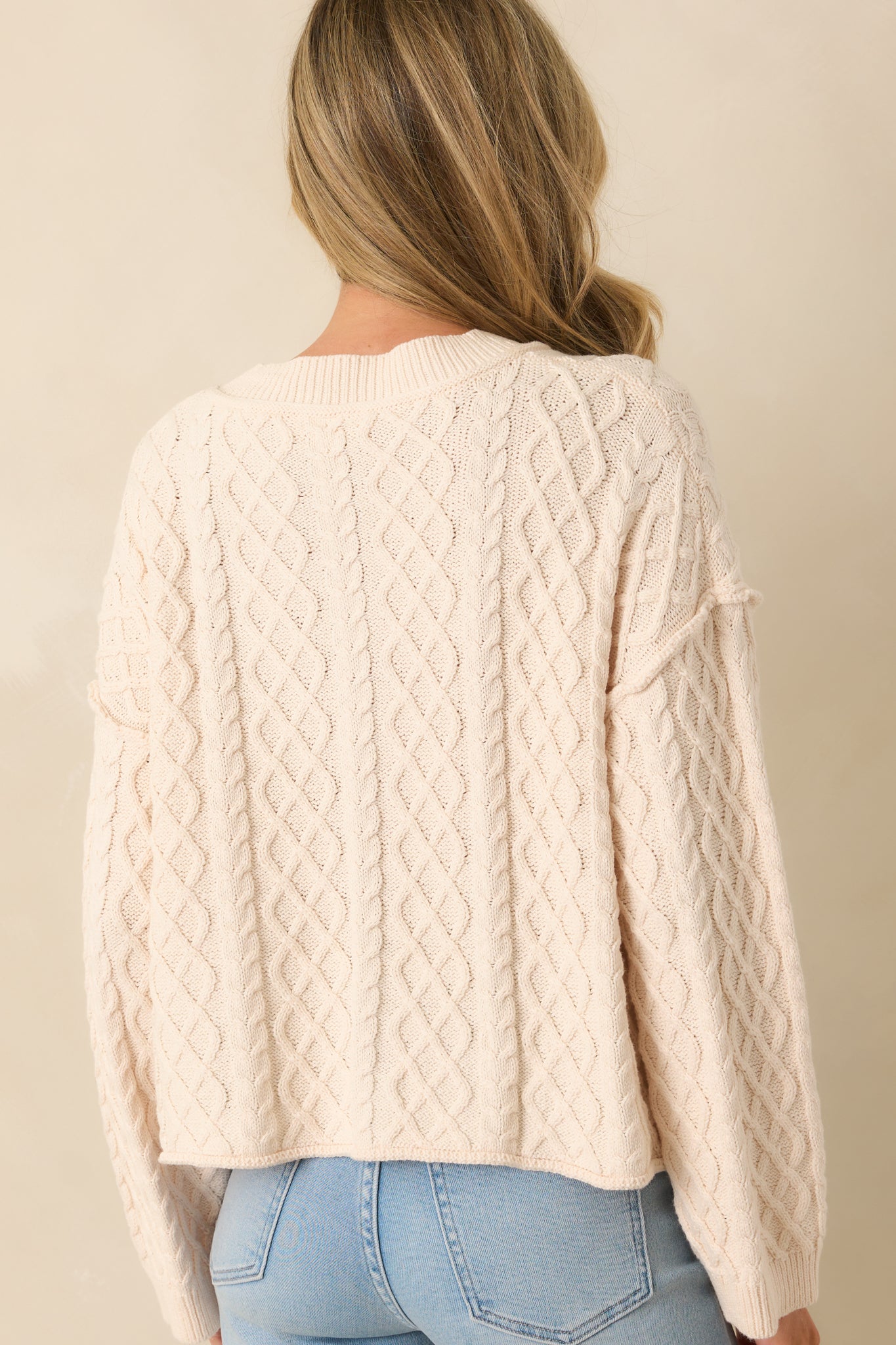 Rear view of the cardigan showing the relaxed silhouette and cable knit texture.
