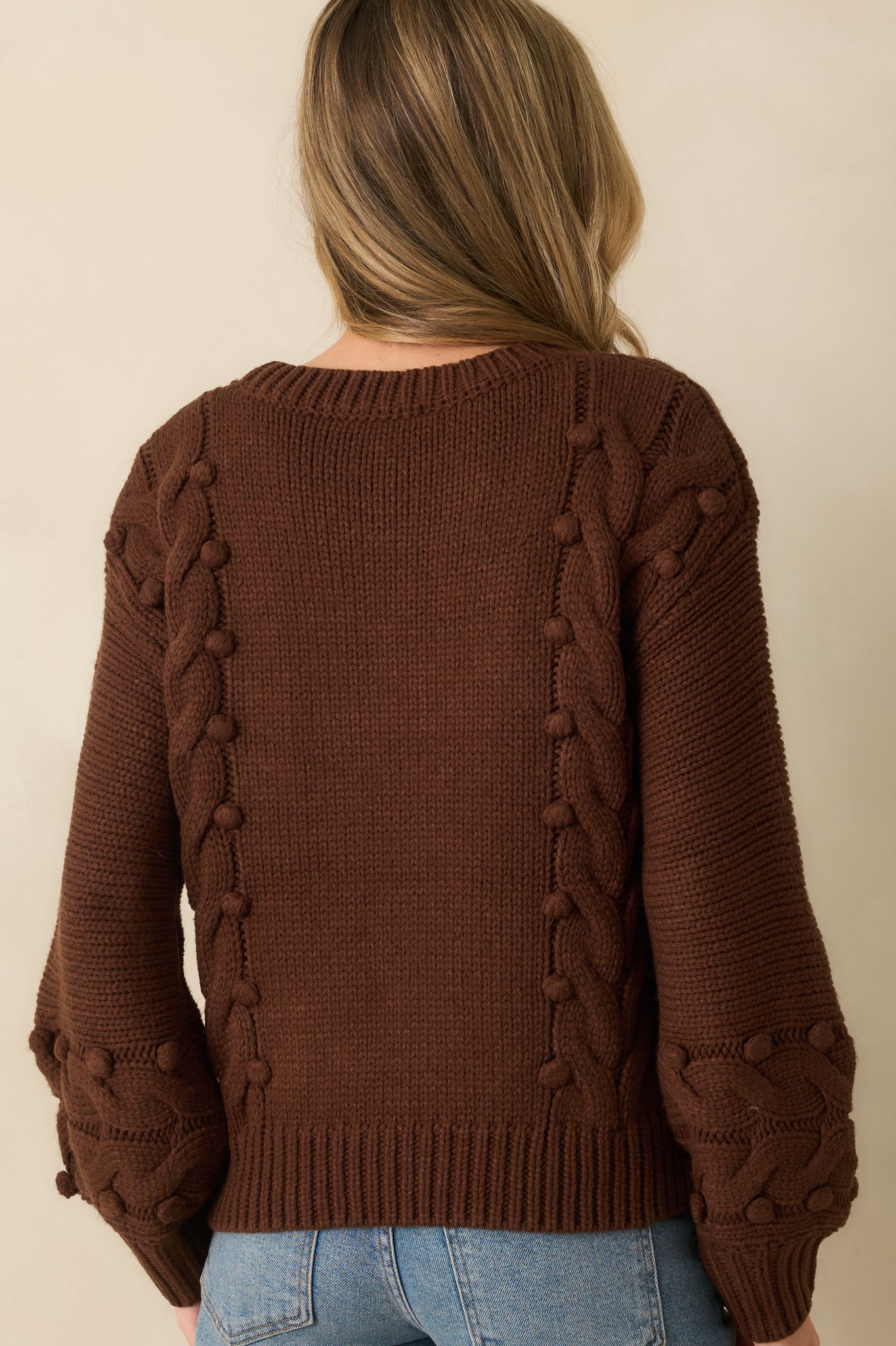 Rear view of the chocolate brown sweater with long sleeves and ribbed trim.