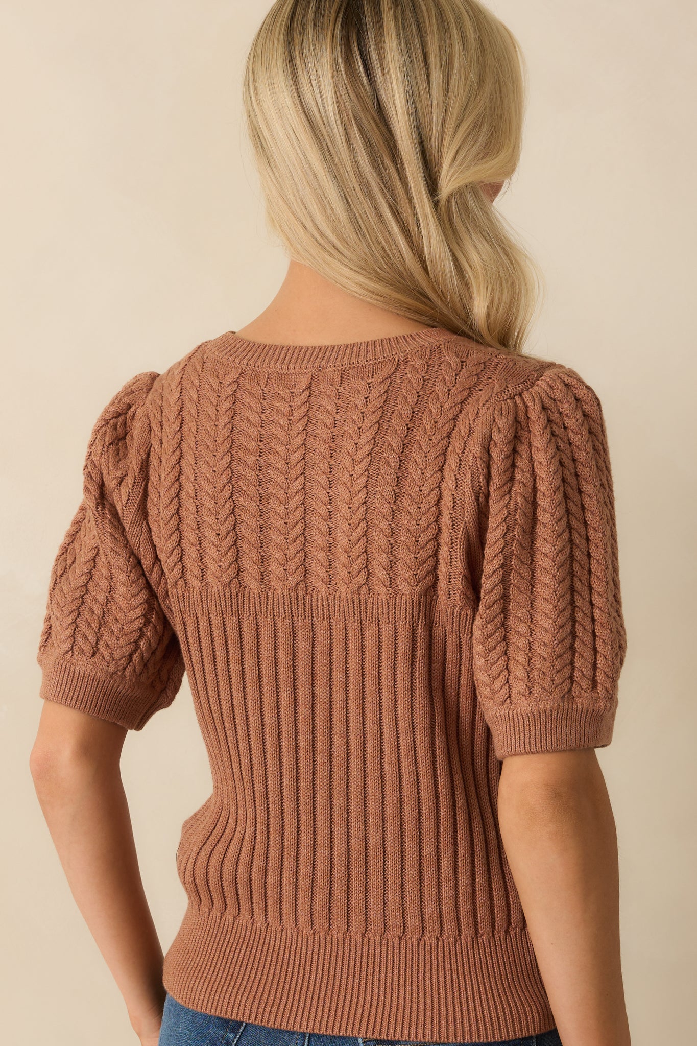 Rear view of the clay brown sweater with ribbed knit body and cable knit sleeves.
