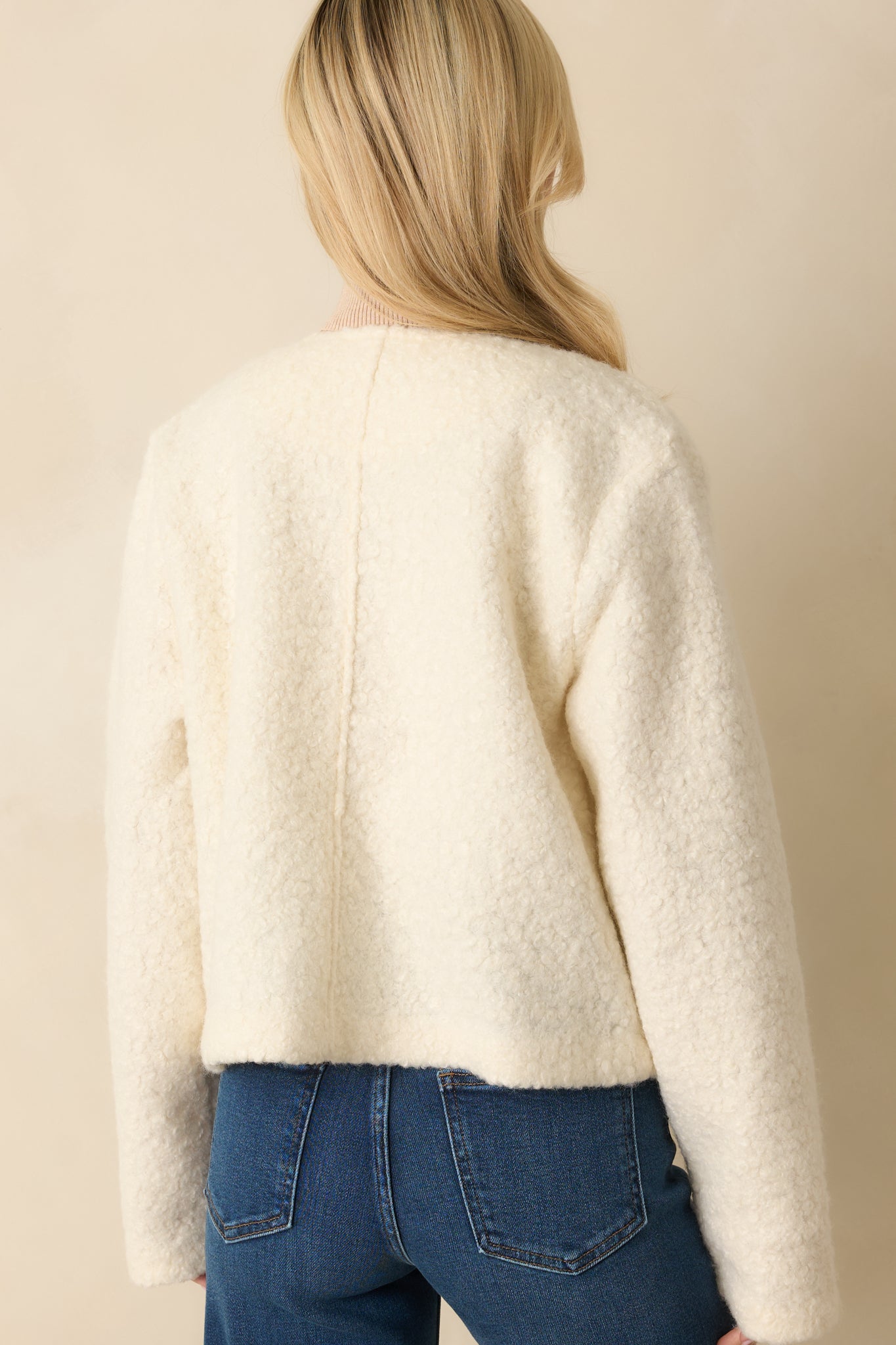 Rear view of the cream bouclé jacket highlighting the long sleeves and soft, structured silhouette.