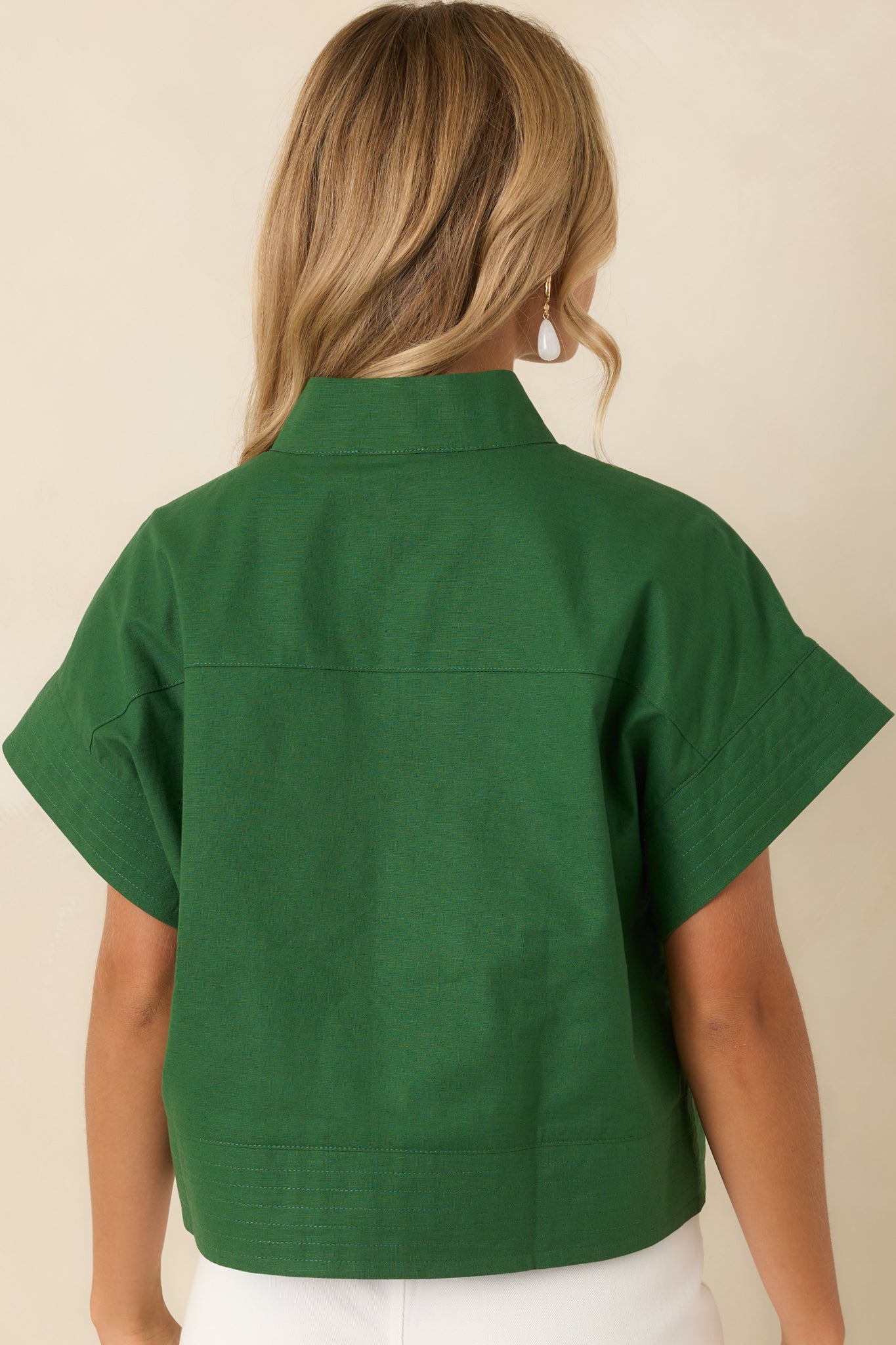 Rear view of the cropped cotton linen top featuring relaxed drop shoulders, cuffed sleeves, and subtle hem stitching.