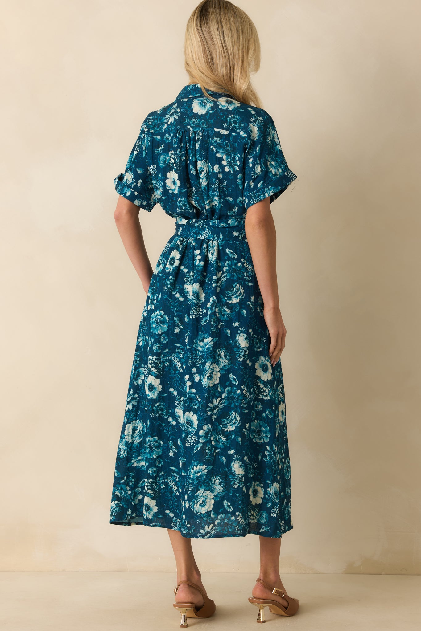 Rear view of the dark teal floral dress showing the elastic waistband, pull-through belt, and cuffed short sleeves.