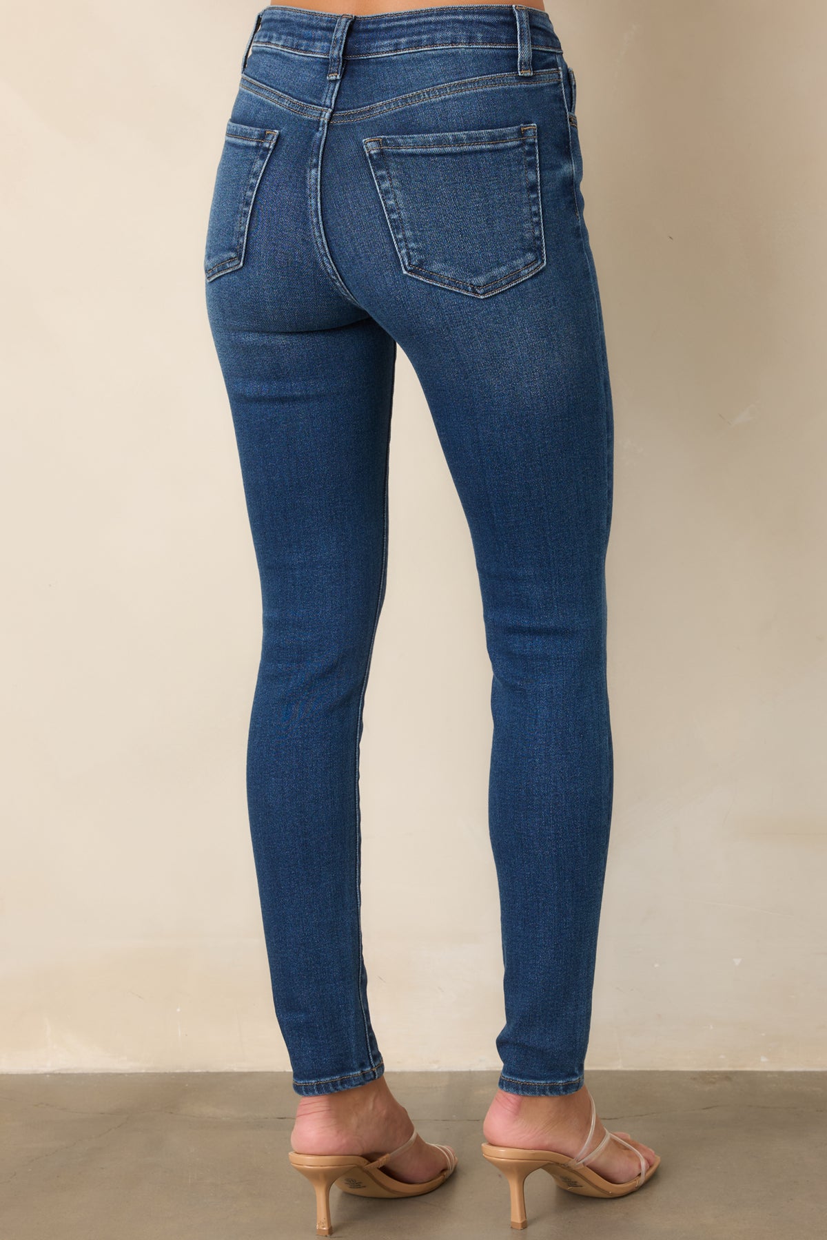 Rear view of dark wash high-rise jeans highlighting the five-pocket design and slim fit.