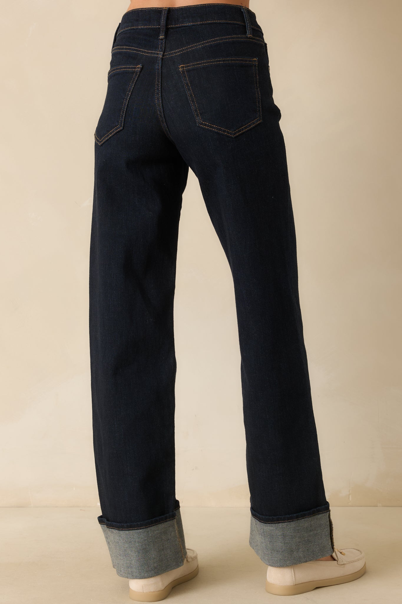 Rear view of dark wash jeans showing high-rise waist, back pockets, wide-leg silhouette, and cuffed hems.