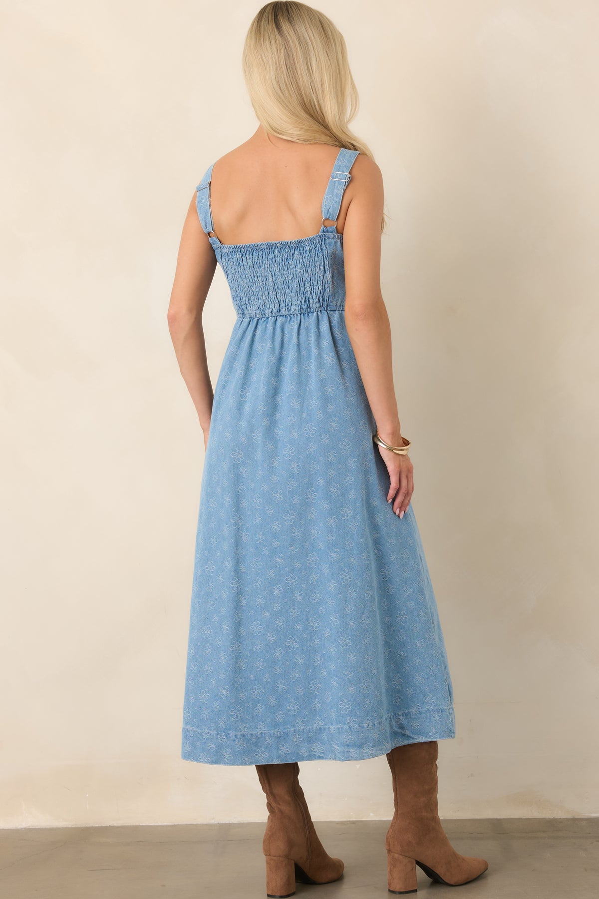 Rear view of the denim midi dress featuring adjustable straps, a smocked back panel, and tonal floral print.