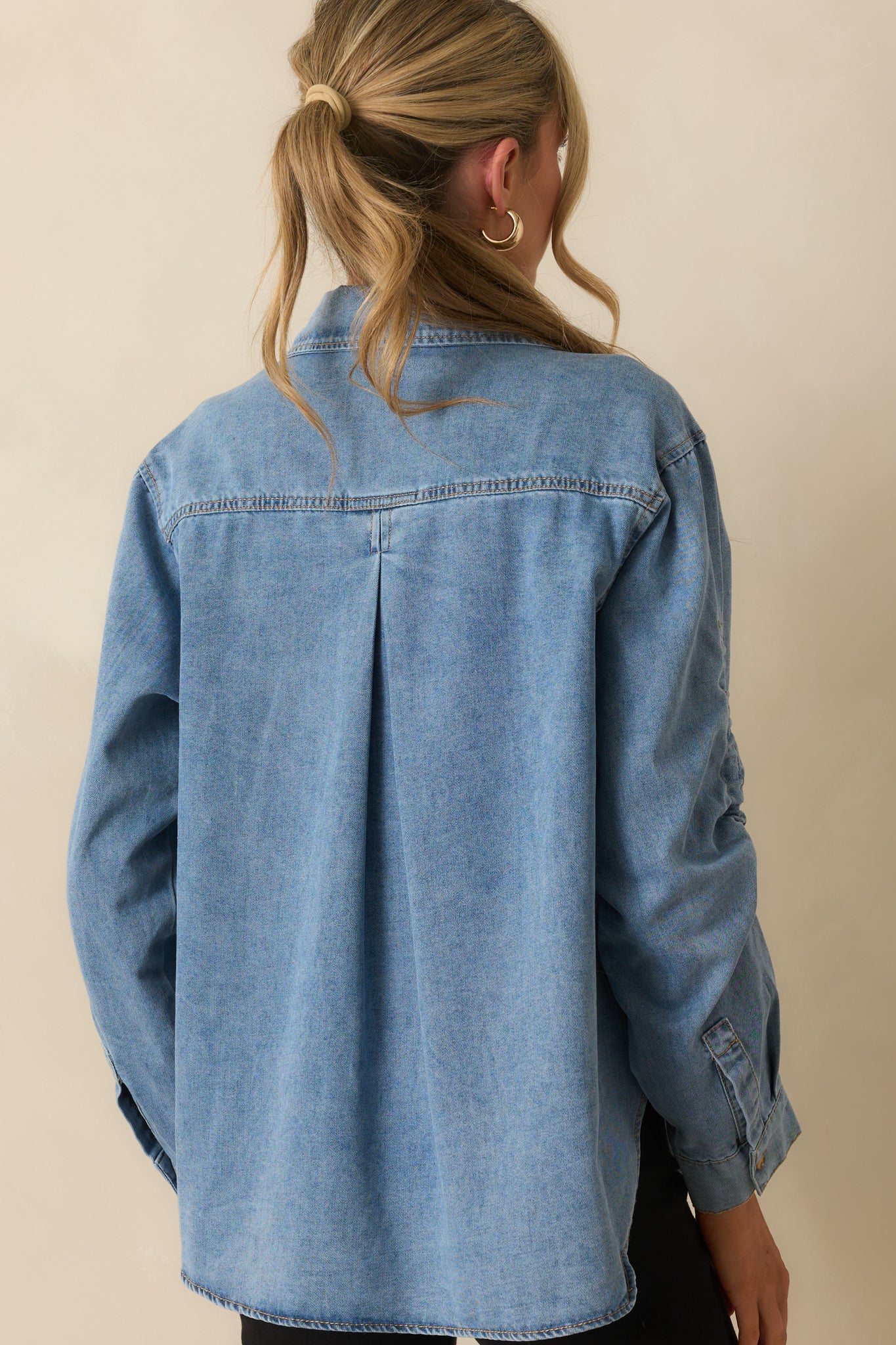 Rear view of denim top showing back yoke with center pleat and scoop hemline.