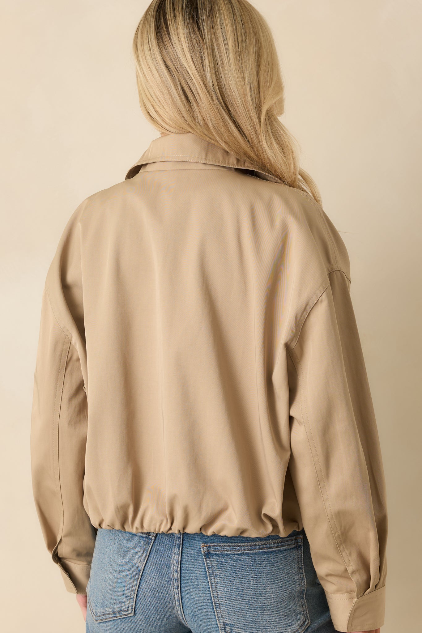 Rear view of the khaki bomber jacket displaying elasticized back hem and relaxed, slightly cropped fit.