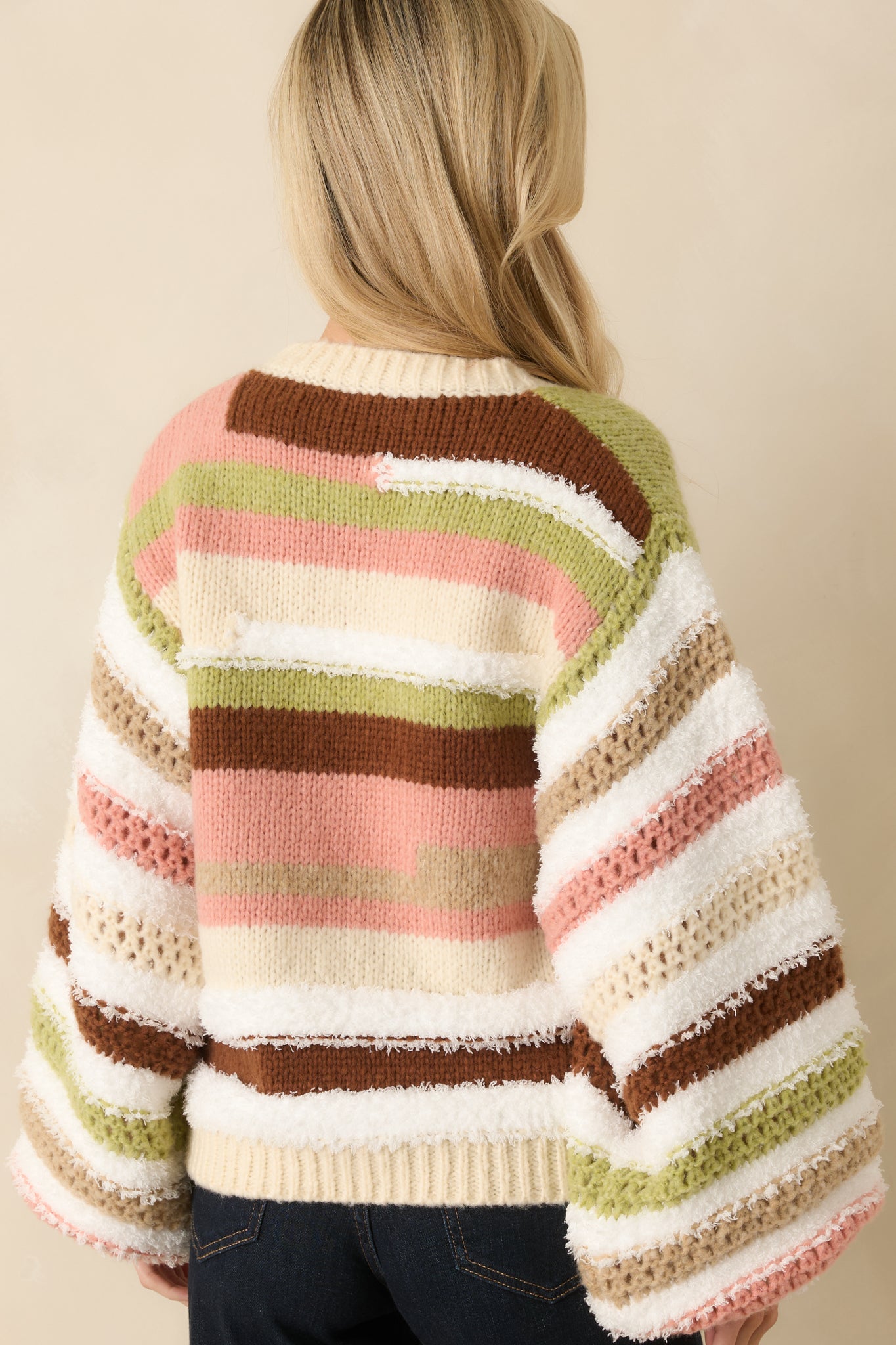 Rear view of oversized ivory striped sweater displaying horizontal stripes, ribbed hem, and long sleeves.