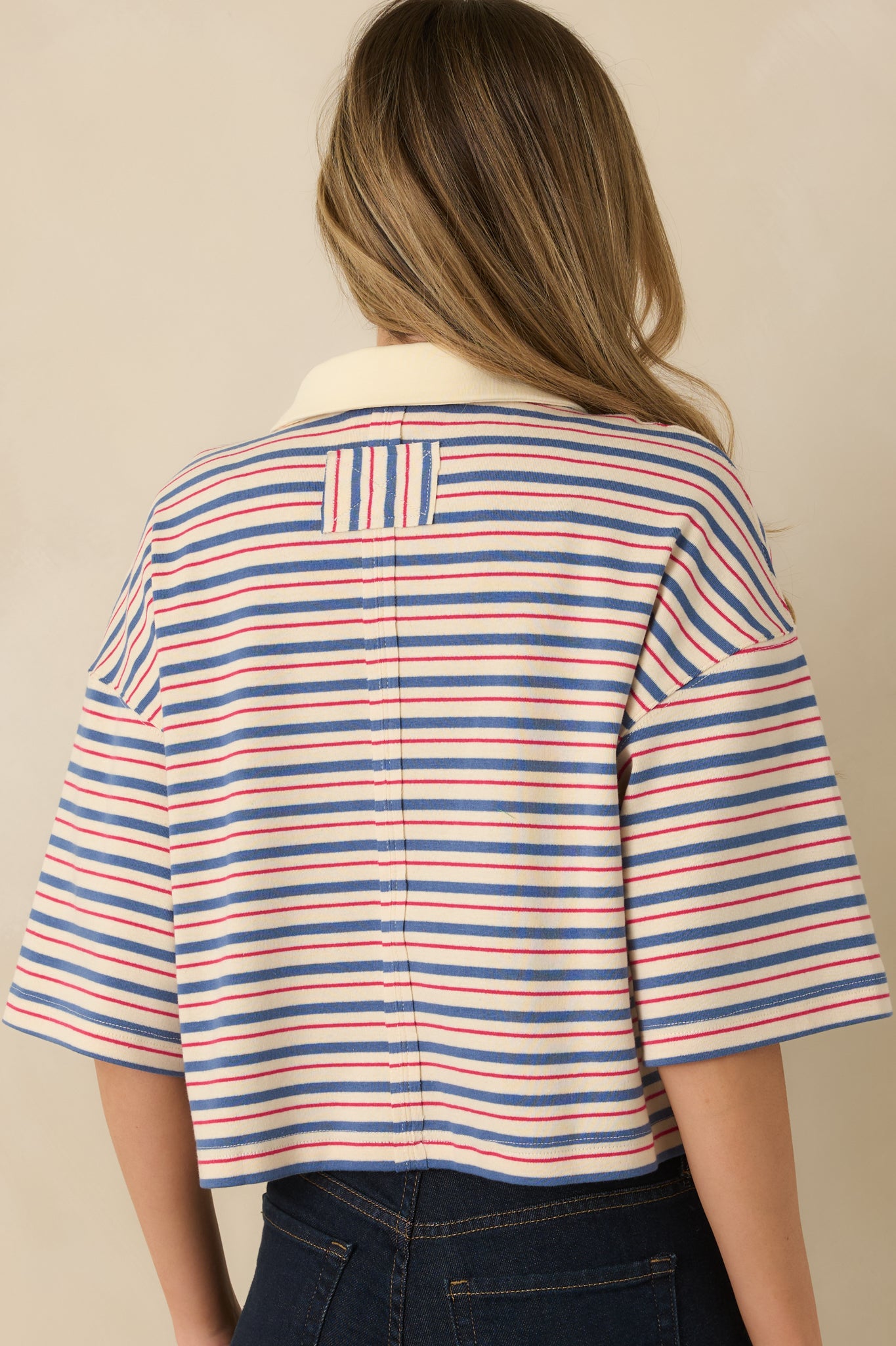 Rear view of the blue multi-stripe top displaying short sleeves and relaxed boxy silhouette.
