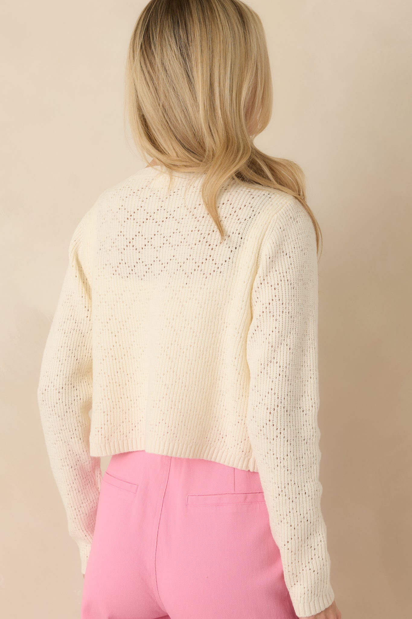 Rear view of the ivory knit cardigan displaying the allover pink rose embroidery across the soft, lightweight fabric.