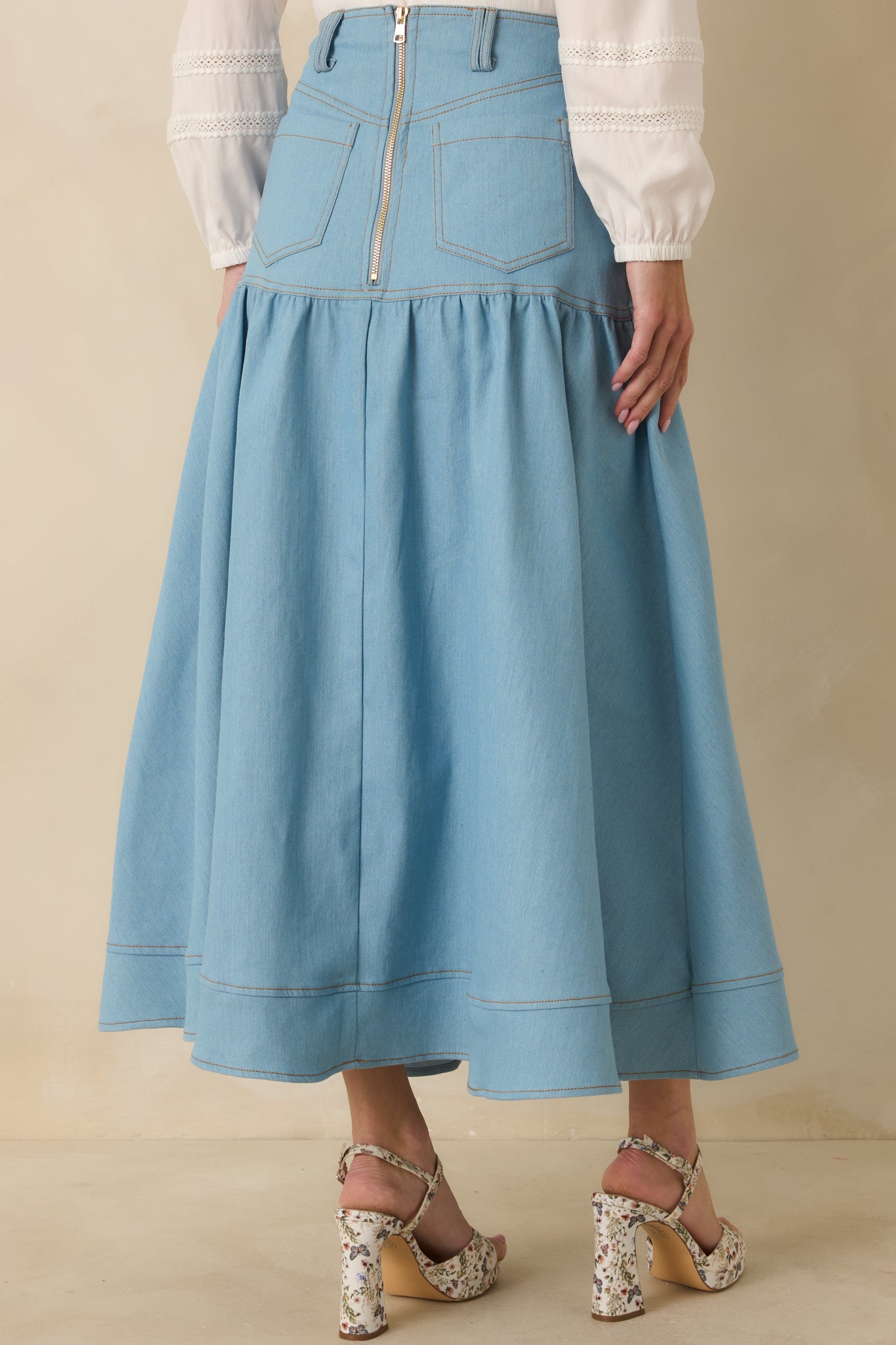 Rear view of the light wash denim maxi skirt displaying back pockets, structured waistband, and zipper closure.