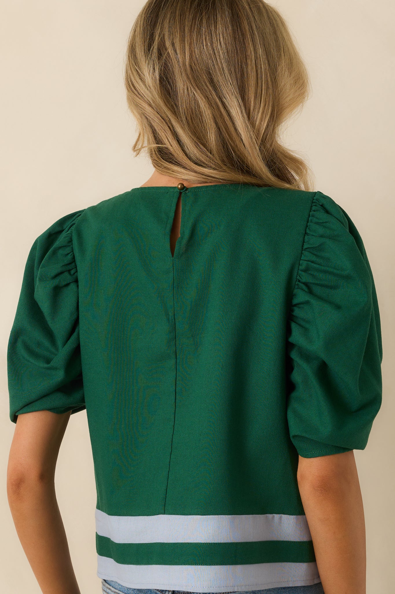 Rear view of green top displaying keyhole button closure, short puff sleeves, and relaxed silhouette.