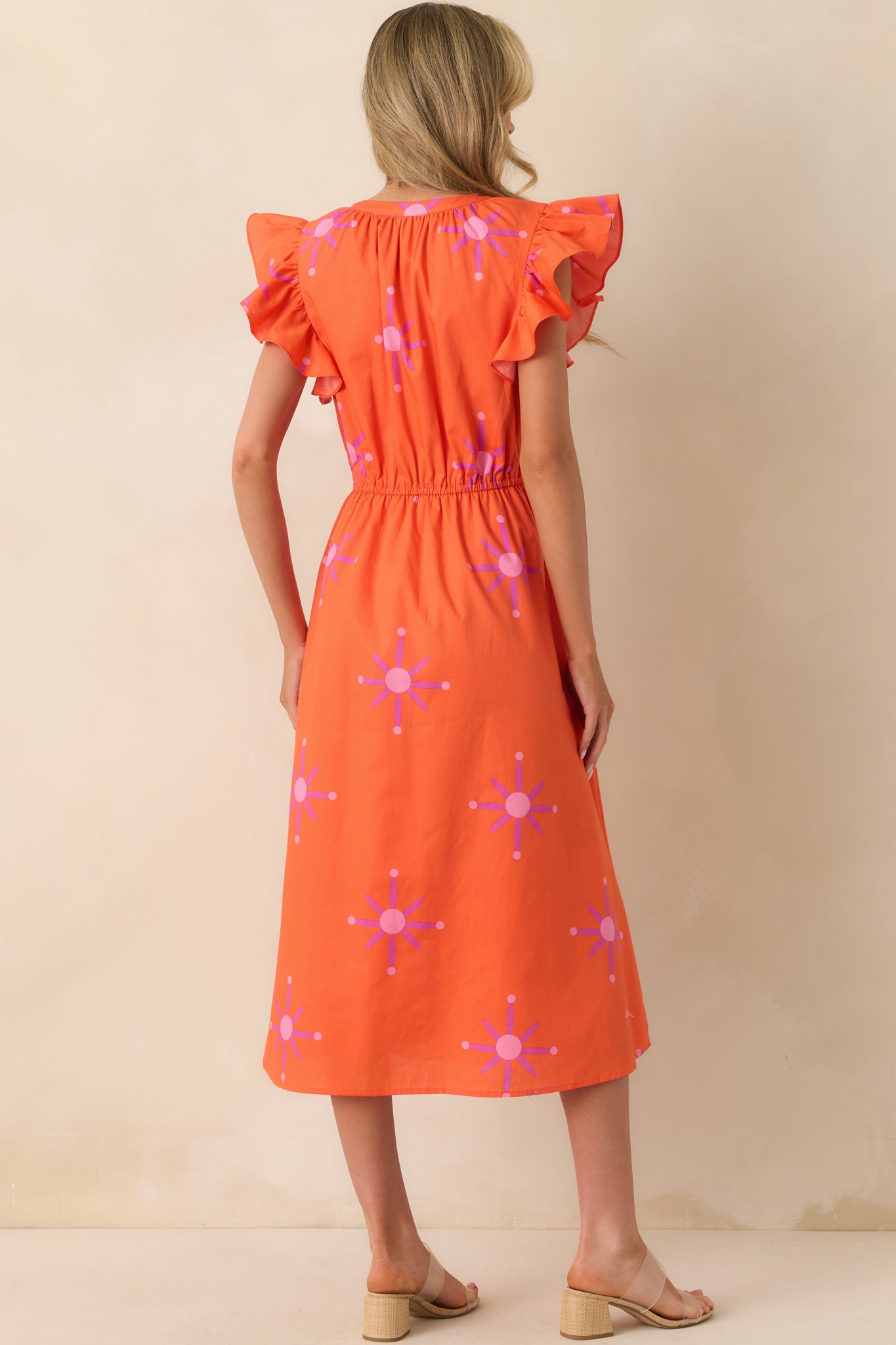 Back view of the dress displaying the elastic waistband and flow of the orange fabric from behind.