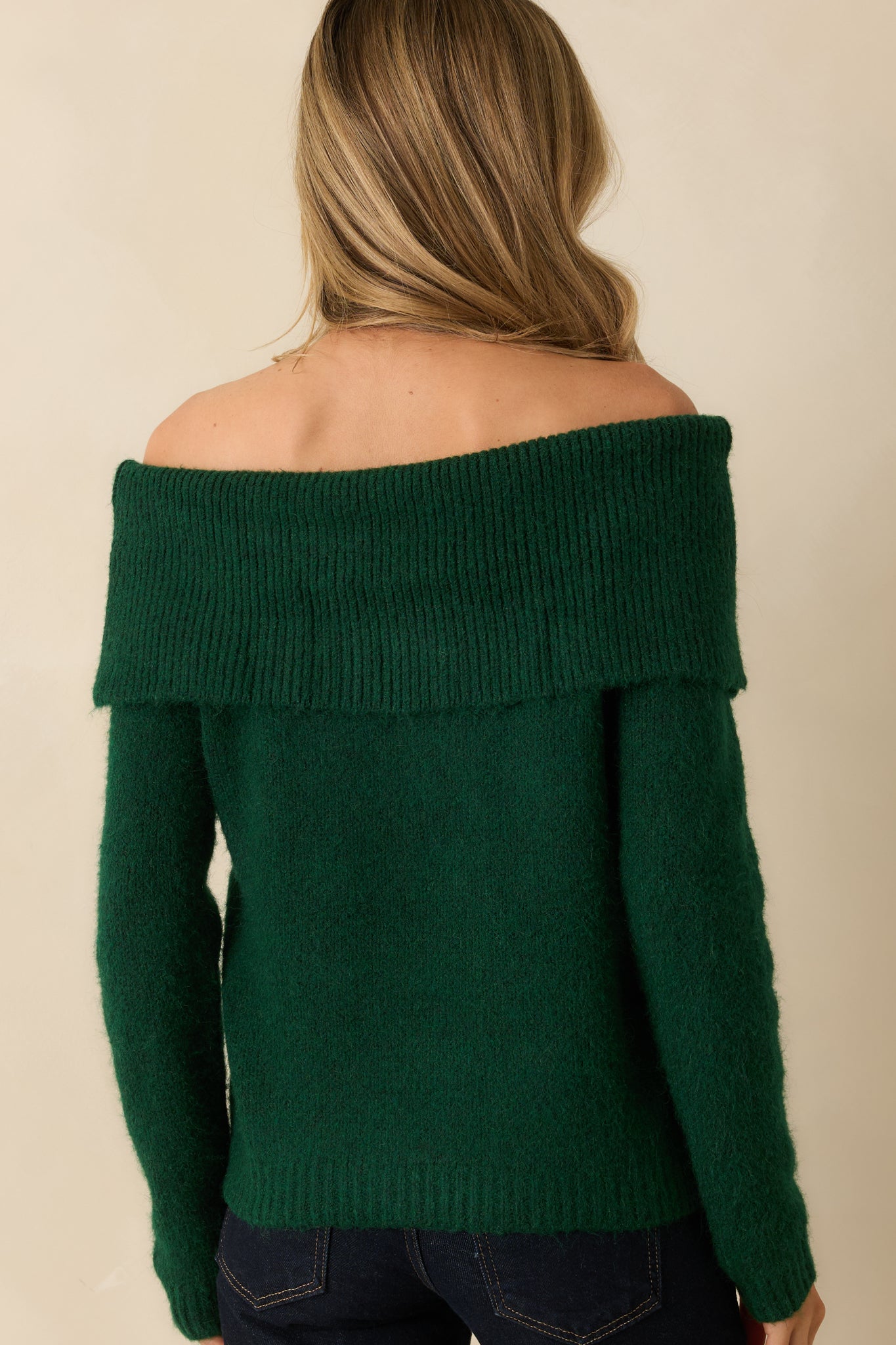 Rear view of the emerald off-shoulder sweater highlighting the relaxed fit, long sleeves, and ribbed hem and cuffs.