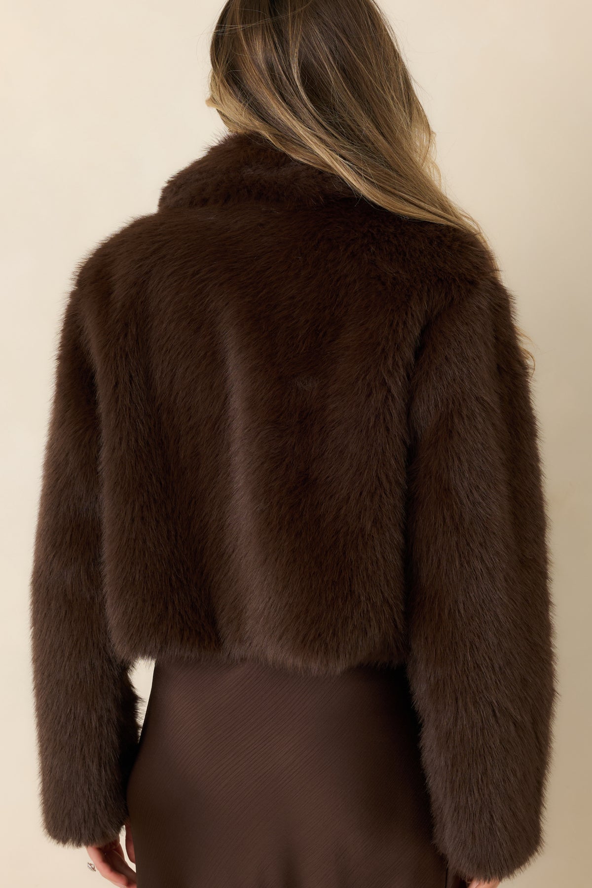 Rear view of the faux fur coat showing its relaxed silhouette and long sleeves.