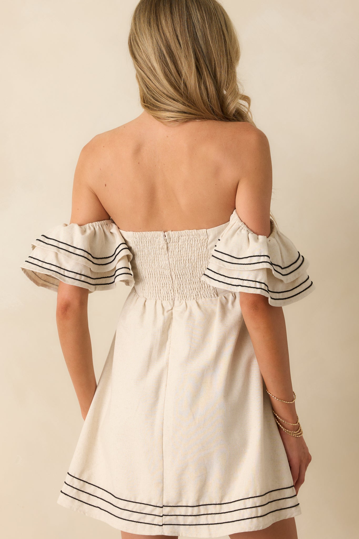 Rear view of the mini dress featuring a smocked panel and hidden zip closure.