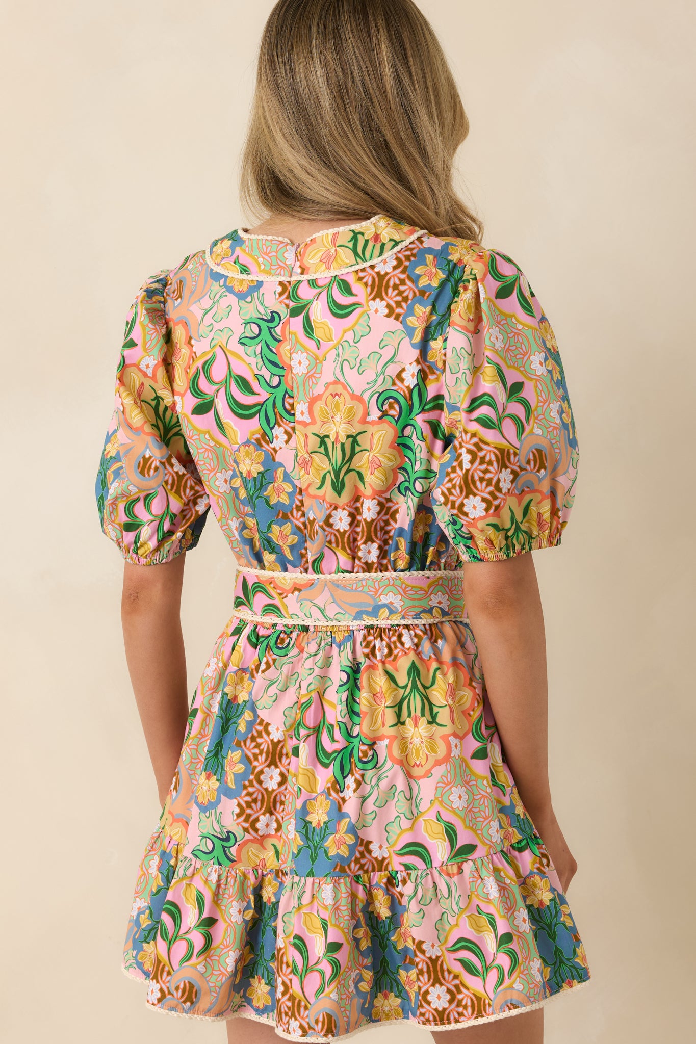 Rear view of pink multicolor mini dress featuring concealed zipper, cinched waist, and tiered skirt silhouette.