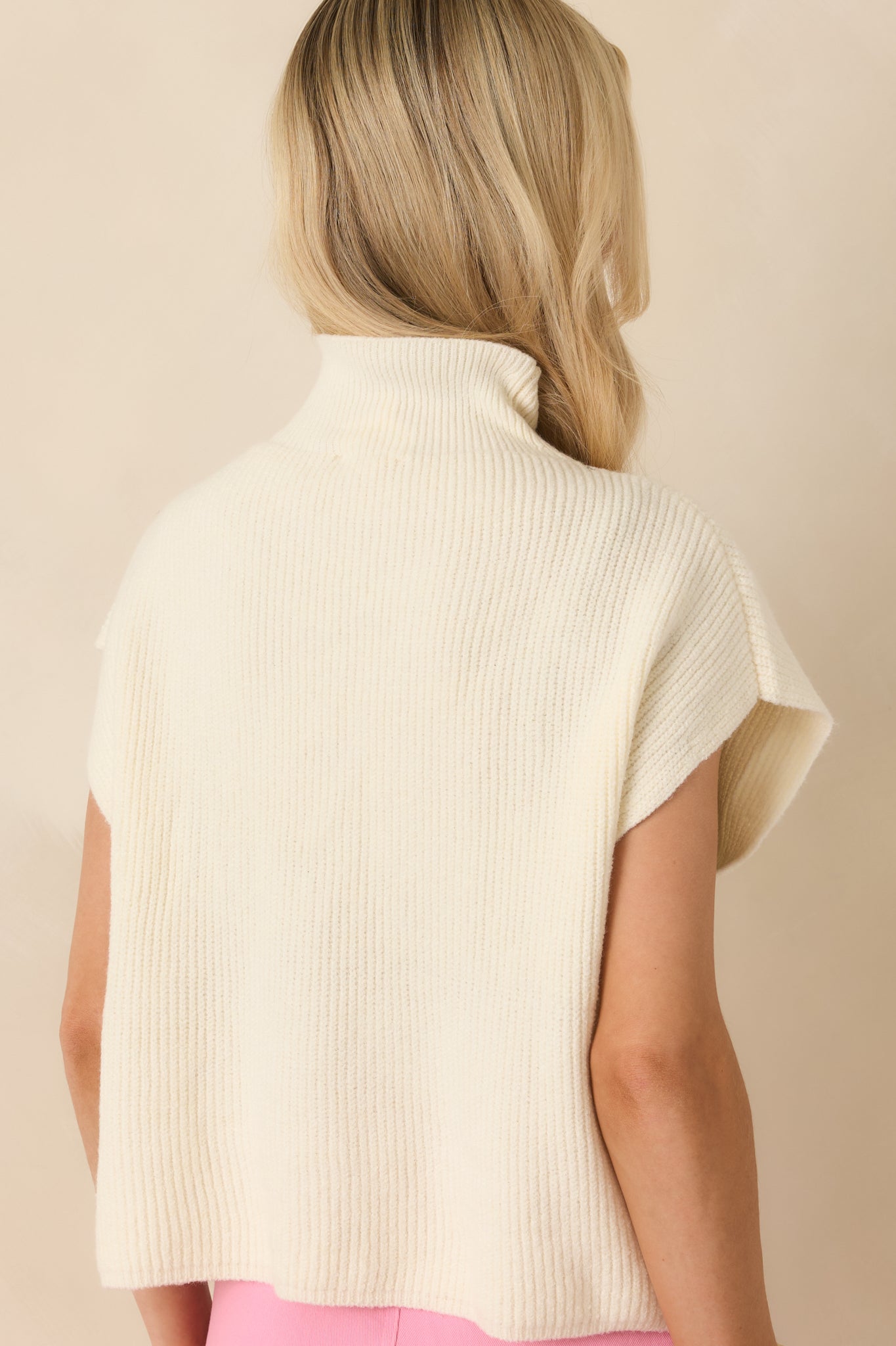 Rear view of the ivory sweater top featuring continuous ribbed knit texture and a clean, smooth hem finish.