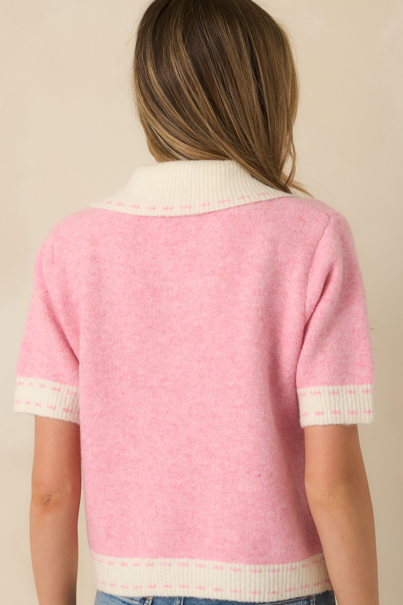 Rear view of pink knit cardigan featuring ivory trim at the collar and hem with a smooth, tailored finish.