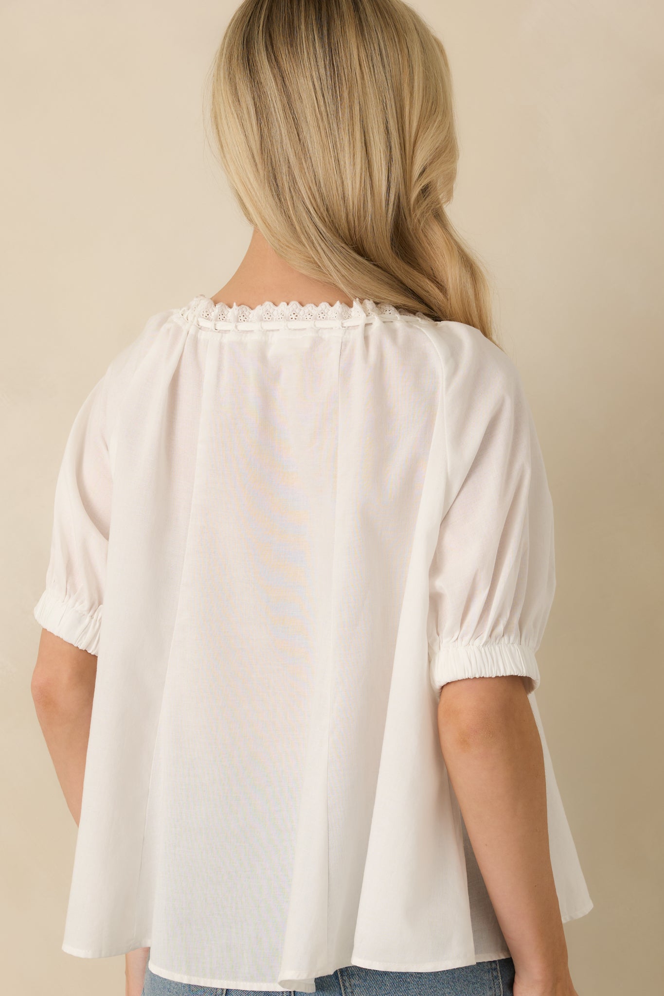 Rear view of white blouse featuring relaxed fit, soft puff sleeves, and gentle drape through the back.