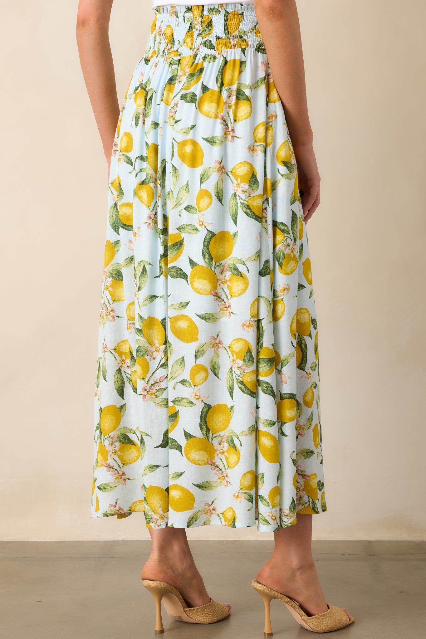 Rear view of skirt featuring smocked waistband insert, lemon print throughout, and gently flared ruffle hem.