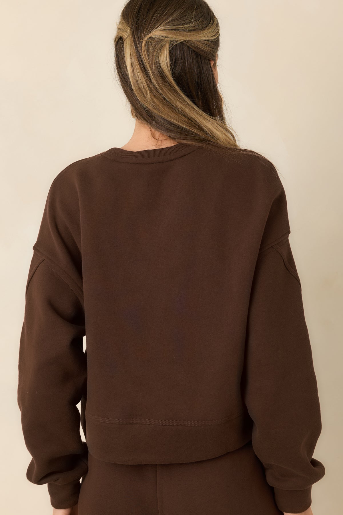 Rear of the relaxed fleece top, showing the dropped shoulders, long sleeves, and simple back design.