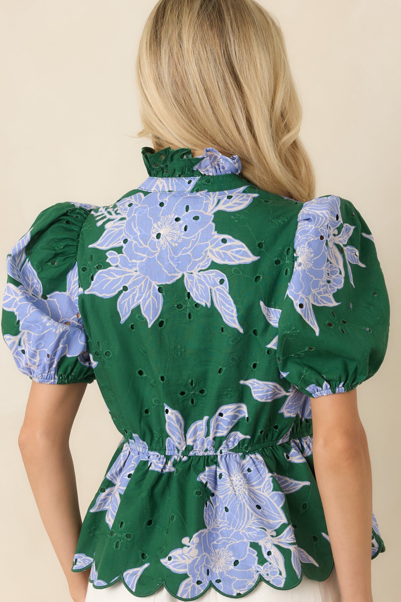 Rear view of the floral cotton top featuring an elasticized back waist, puff sleeves, scalloped hem, and embroidered eyelet fabric.