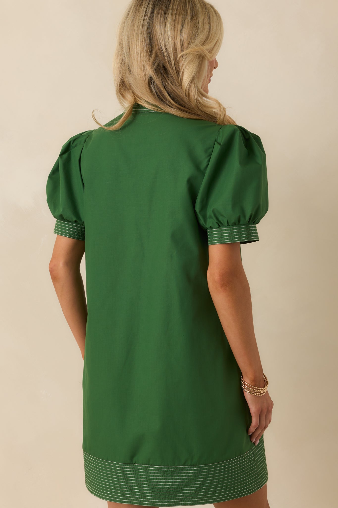 Rear view of forest green mini dress showing short puff sleeves, full lining, and clean topstitch detailing