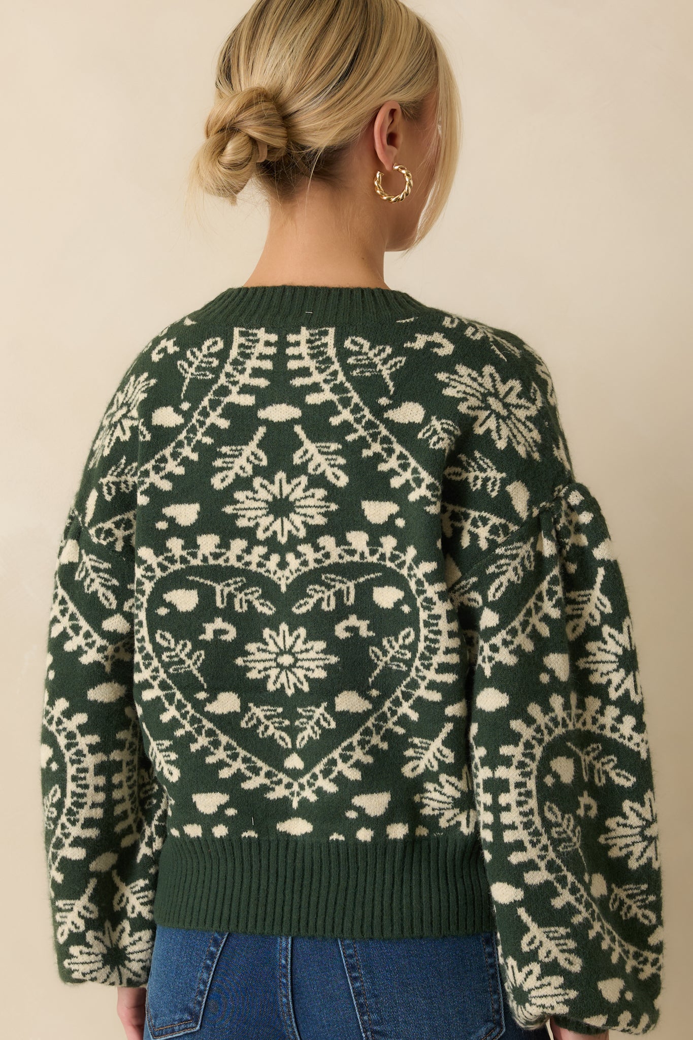 Rear view of the forest green sweater highlighting the pullover fit, drop shoulders, and all-over heart pattern.