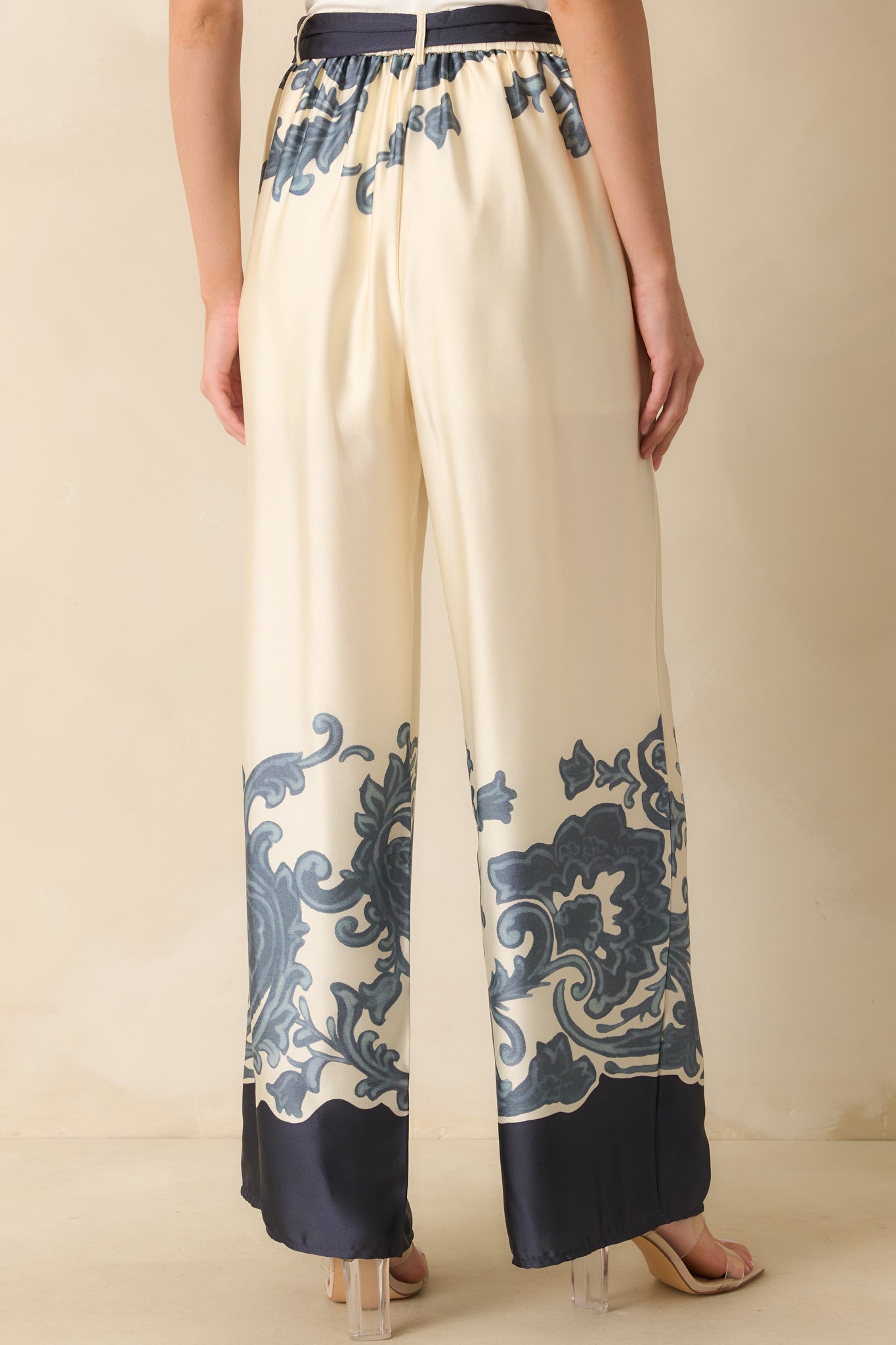 Rear view of ivory pants featuring elastic waistband insert, back pockets, and flowing wide-leg shape.