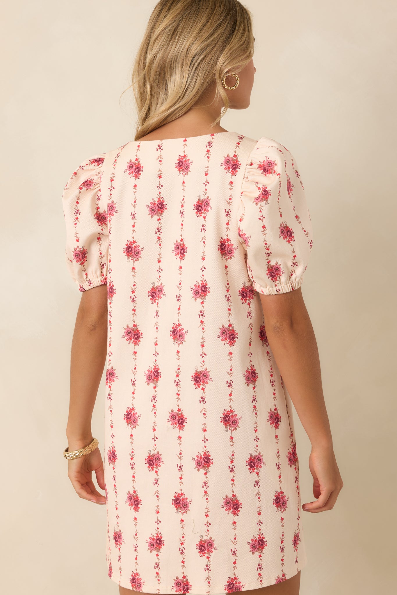 Rear view of the ivory floral mini dress featuring trailing vine print, puff sleeves, structured shape, and smooth finish.