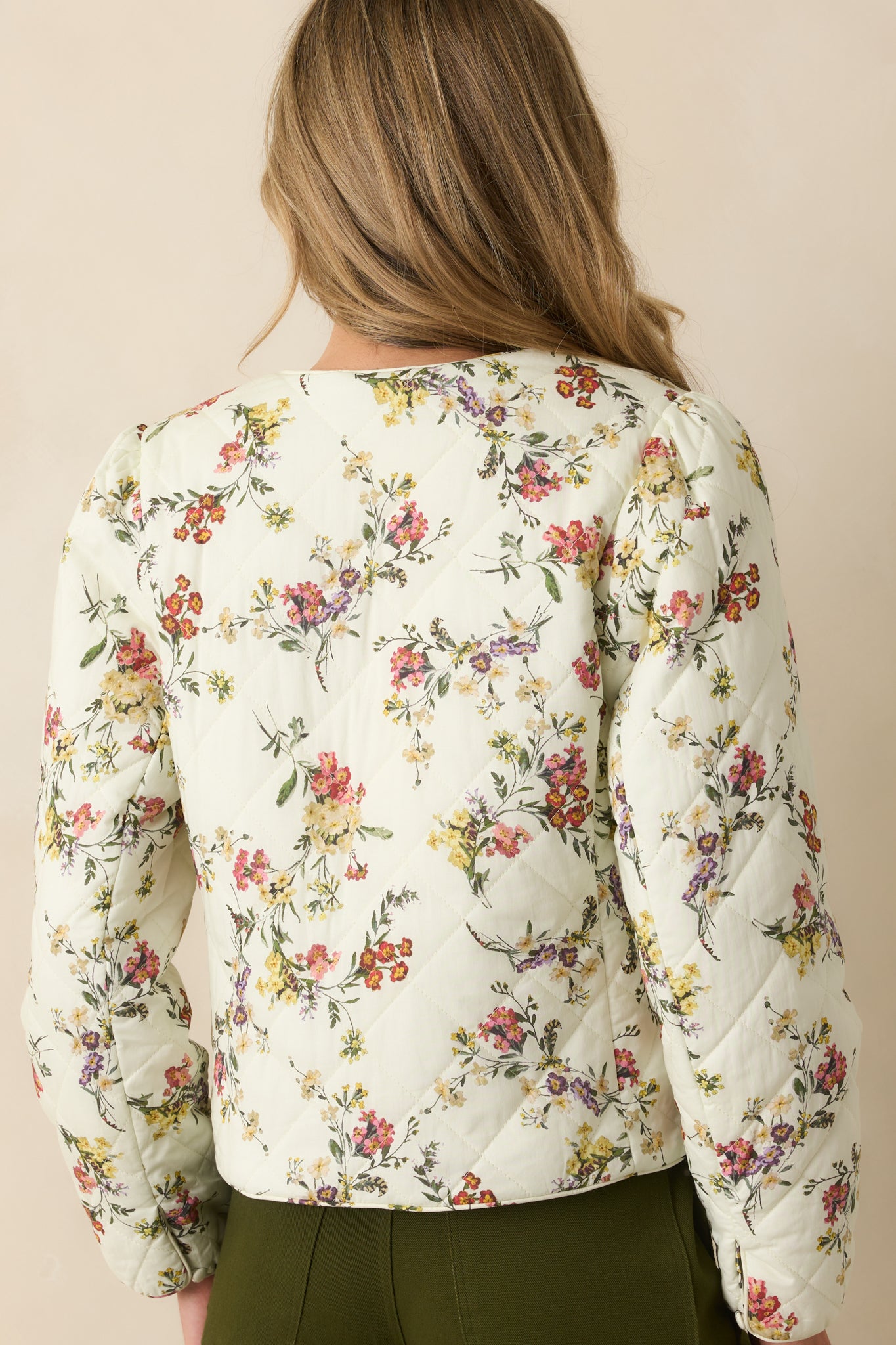 Rear view of ivory jacket showing diamond quilt pattern, long sleeves, and relaxed fit.