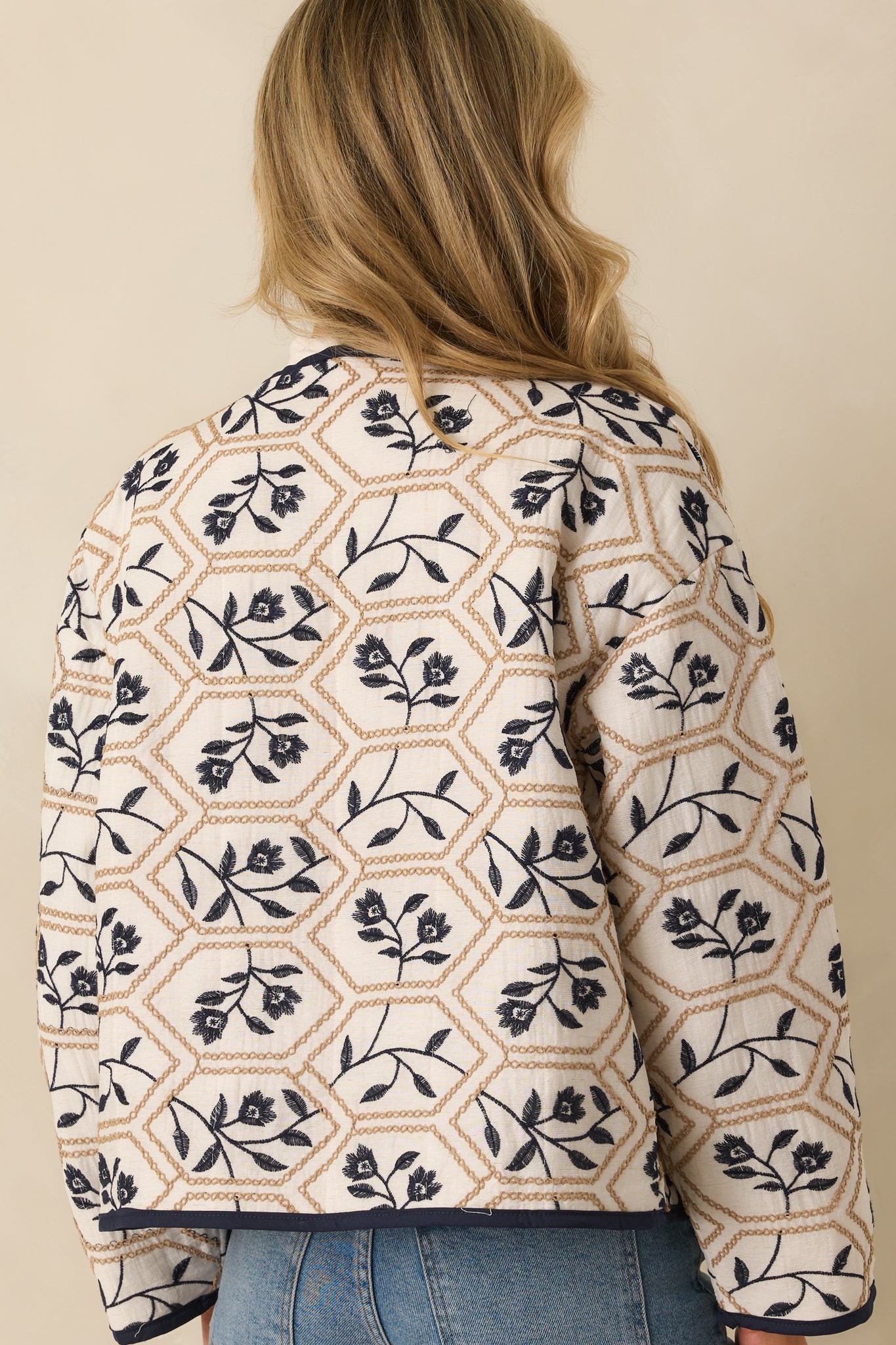 Rear view of ivory jacket featuring embroidered pattern, long sleeves, and relaxed fit.