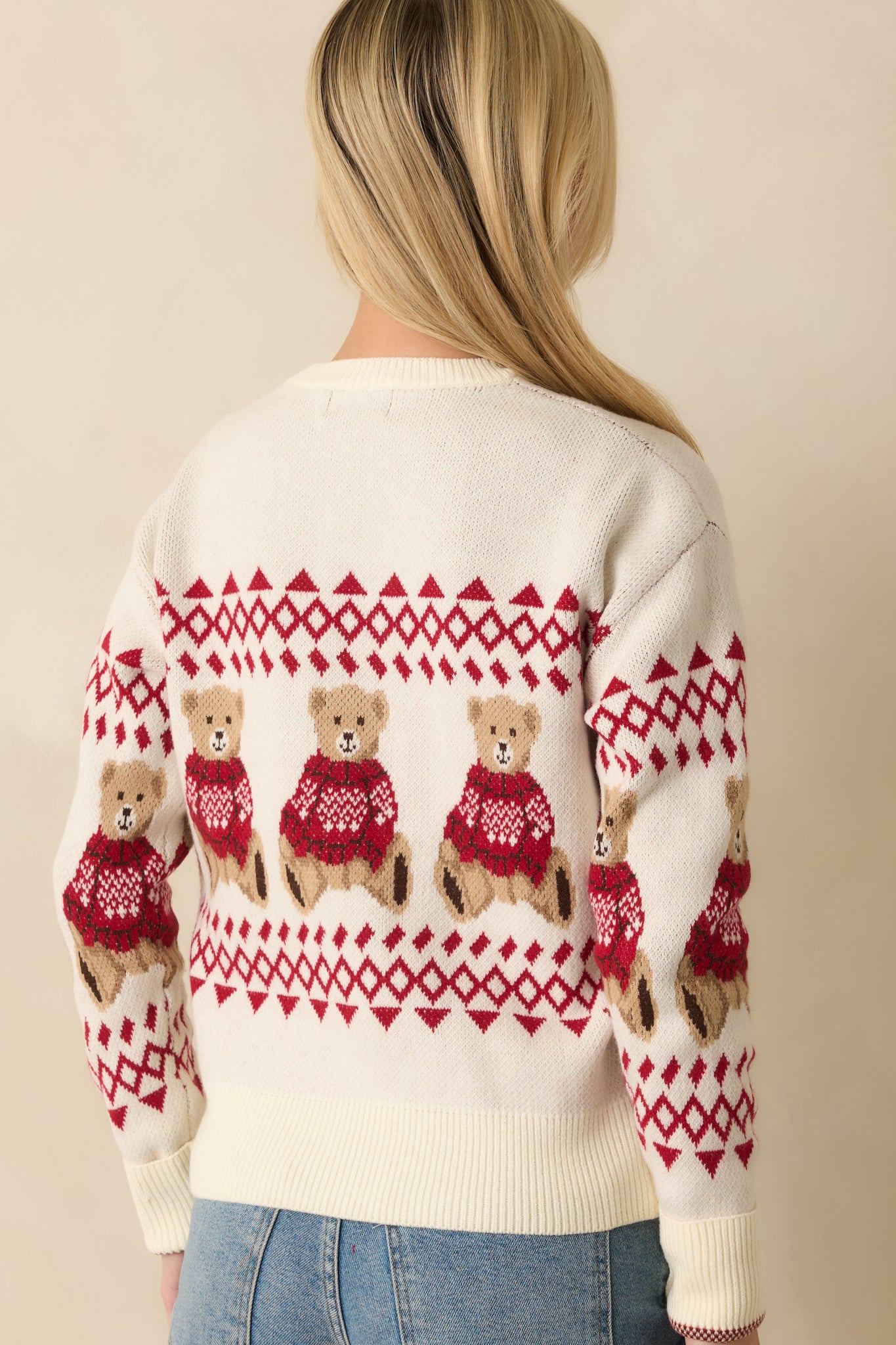 Rear view of the ivory knit sweater highlighting the all-around jacquard patterning and ribbed trim at the neckline, cuffs, and hem.
