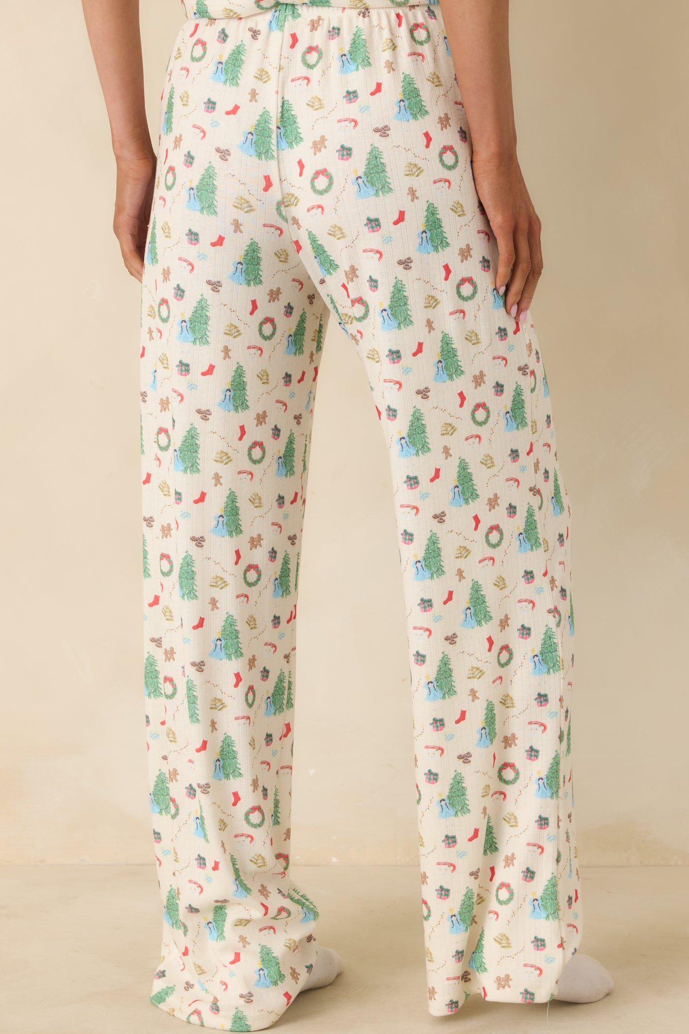 Rear view of the ivory pajama pants displaying the continuous holiday tree print and relaxed straight-leg silhouette.