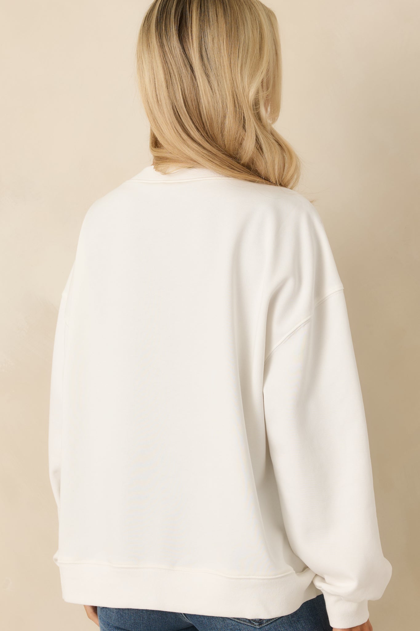 Rear view of white cotton crewneck sweatshirt with ribbed hem and cuffs, keeping the silhouette relaxed and minimal from behind.