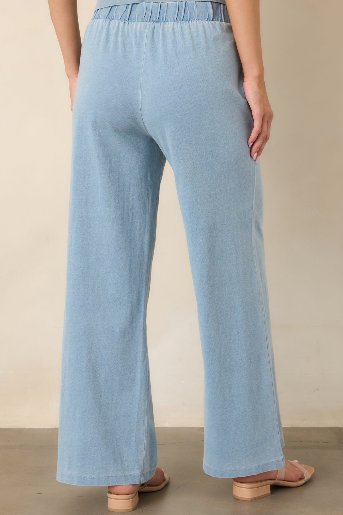 Rear view of the light denim blue lounge pants showcasing the high-rise elastic waistband, relaxed wide-leg silhouette, and soft cotton construction.