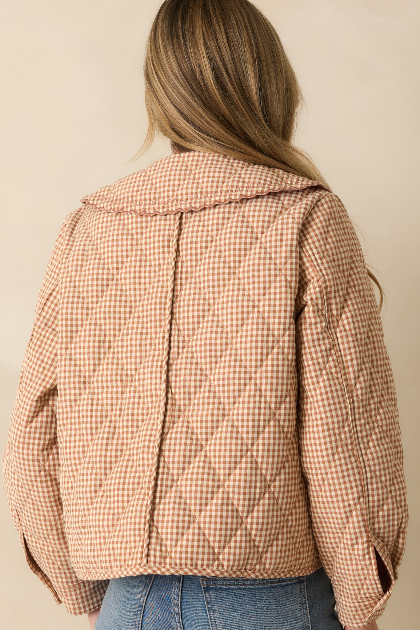 Back view of the light rust gingham jacket showing quilted stitching and scalloped collar.