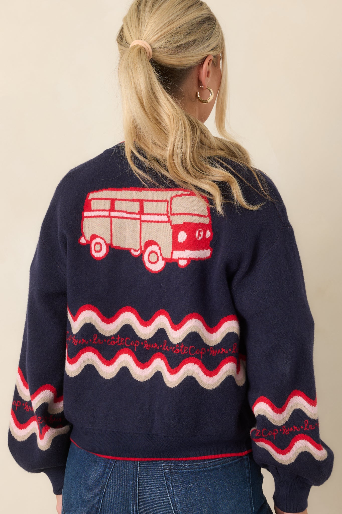 Rear view of the navy cardigan showcasing the camper bus motif, colorful wave detailing, long sleeves, and relaxed knit silhouette.