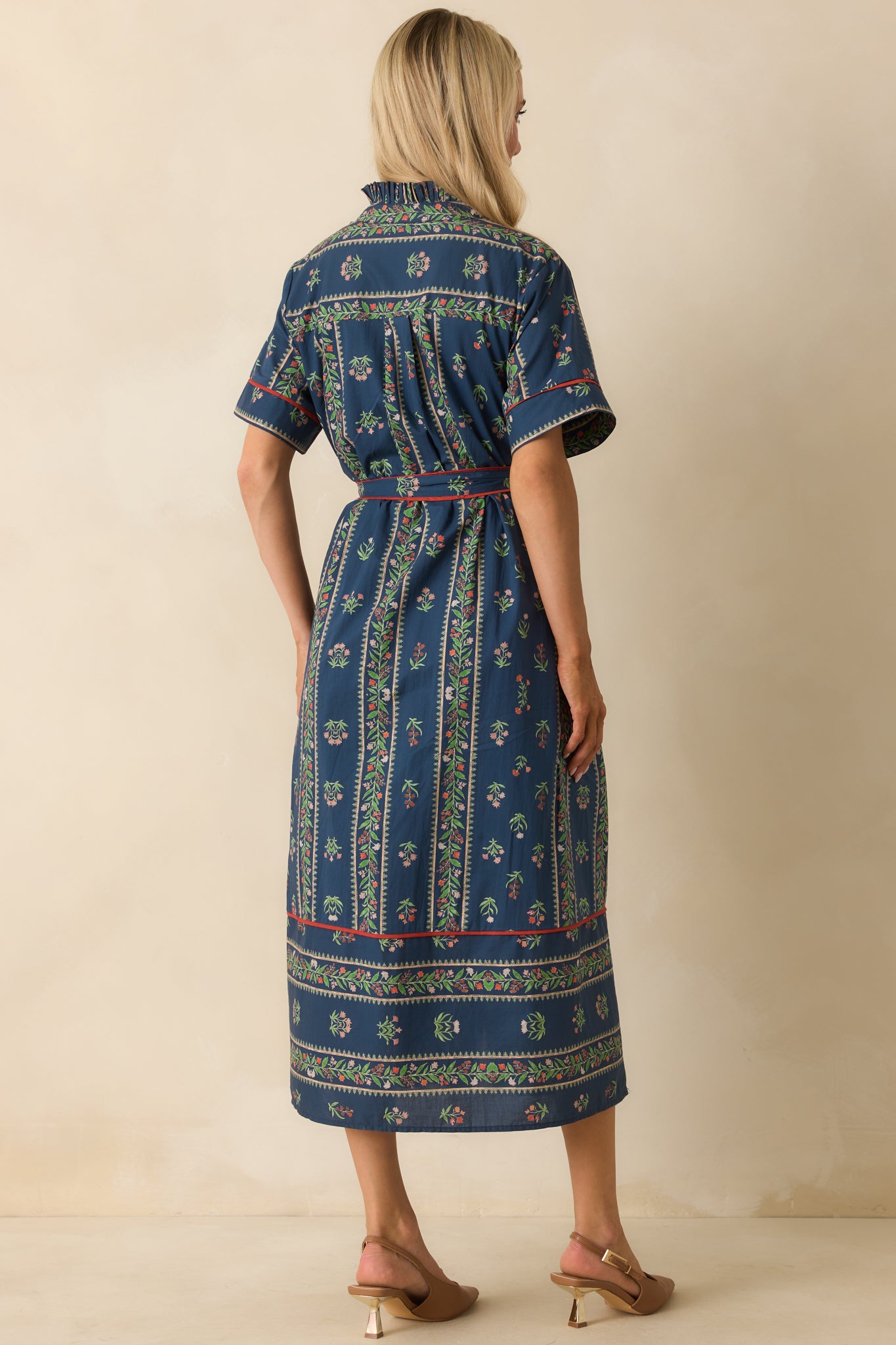 Rear view of the navy maxi dress showing flowing skirt, red piping trim, and short sleeves.