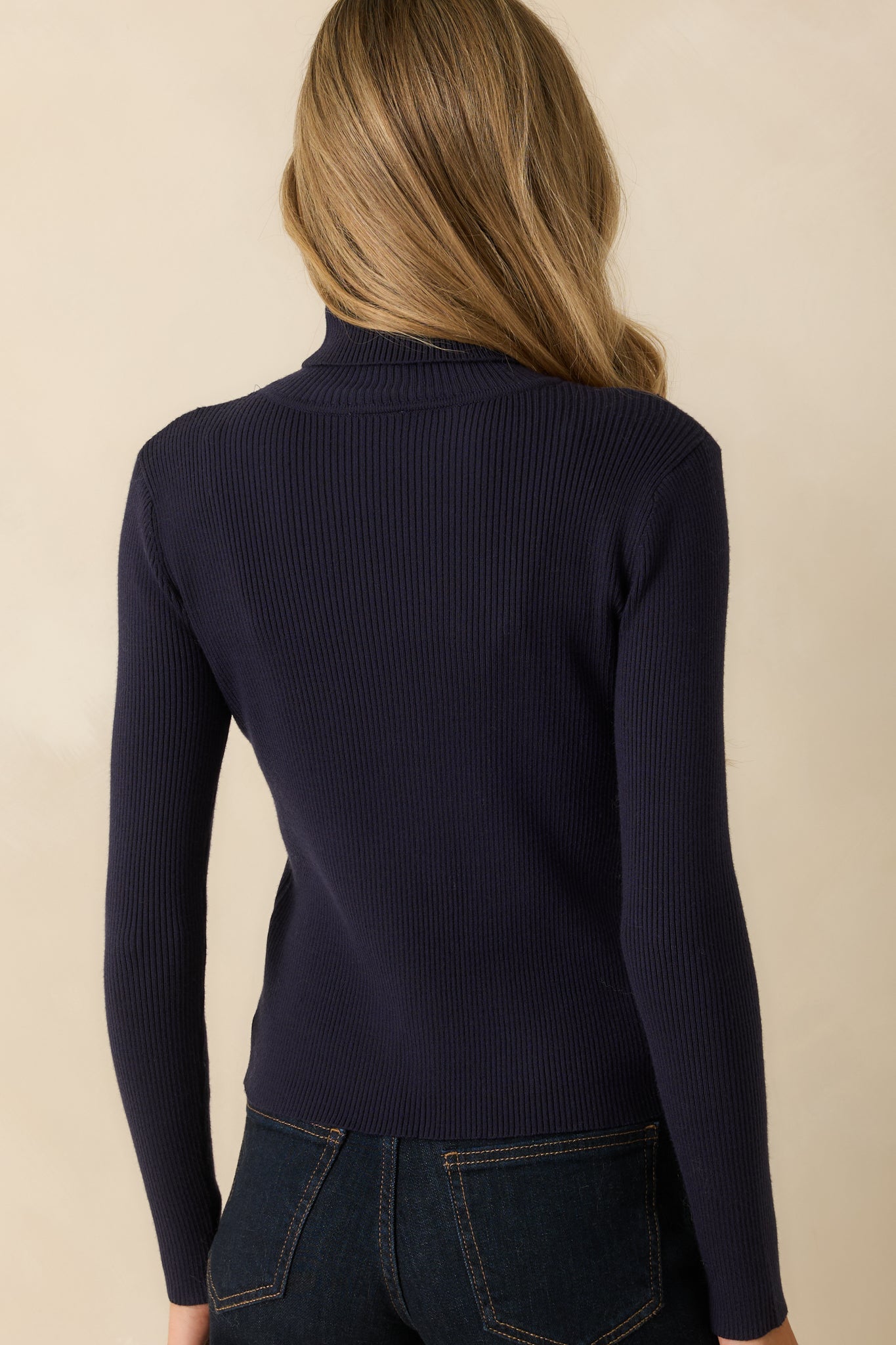 Rear view of the navy ribbed sweater displaying long sleeves, a straight hem, and fitted silhouette.