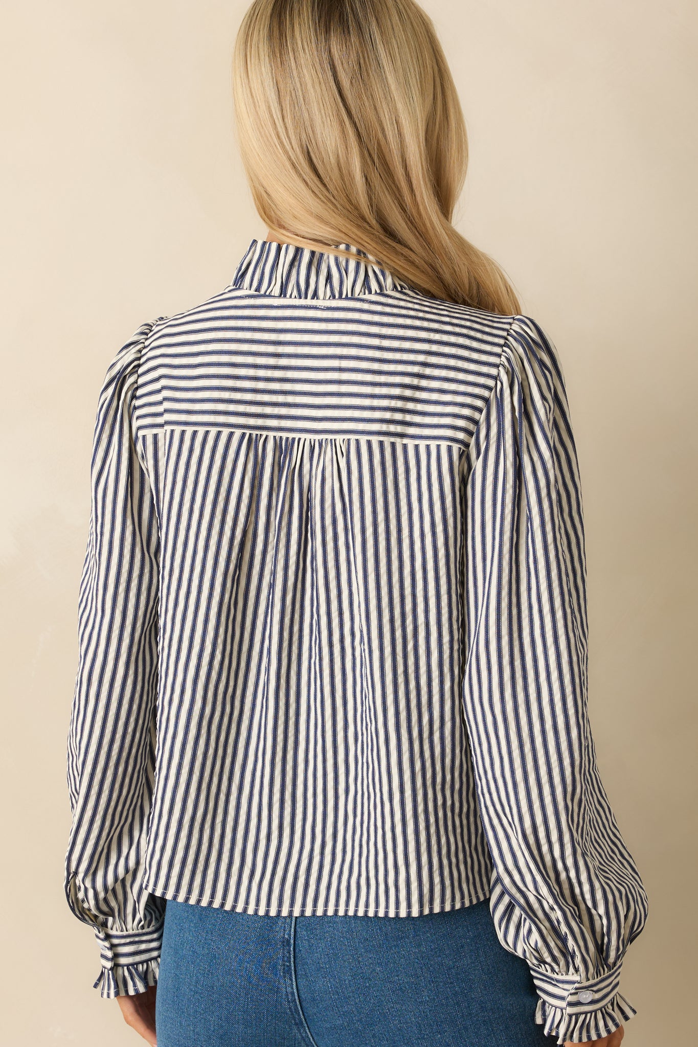Rear view of the navy striped blouse displaying the back yoke pleating and smooth finish.