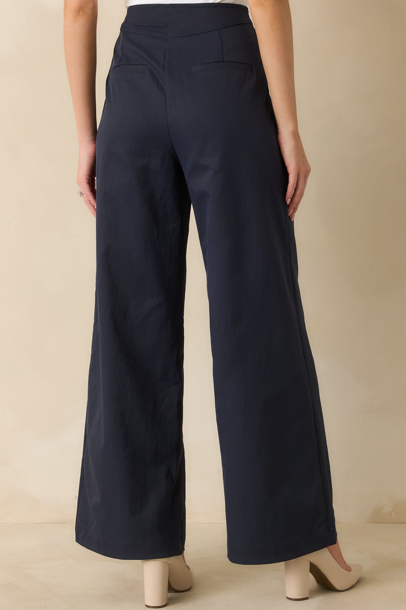 Rear view of navy wide-leg pants showing back welt pockets and full-length flowing legs.