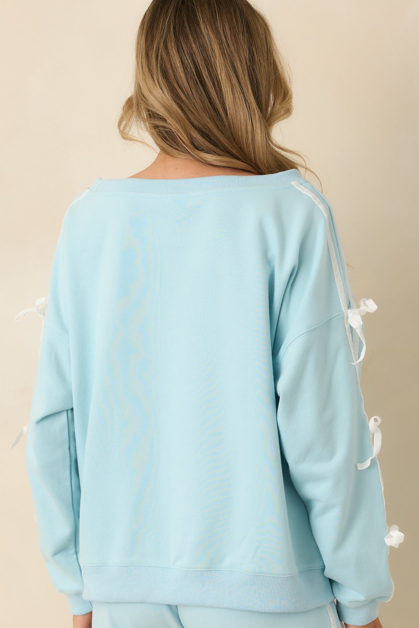 Rear view of aqua sweatshirt showing relaxed fit and ribbed hem and cuffs.