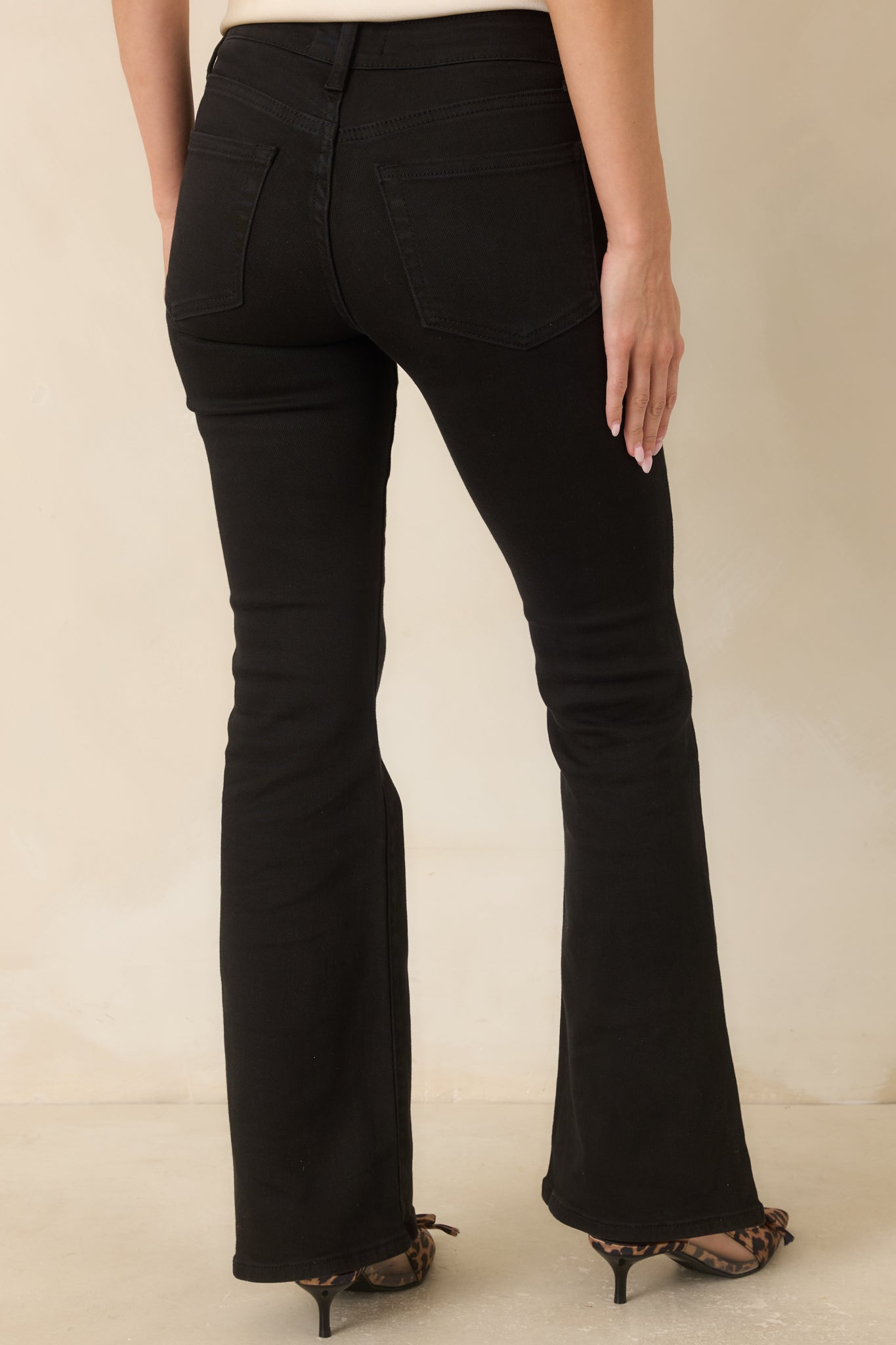Rear view of the black flare jeans showcasing the back pockets and clean finished hems.