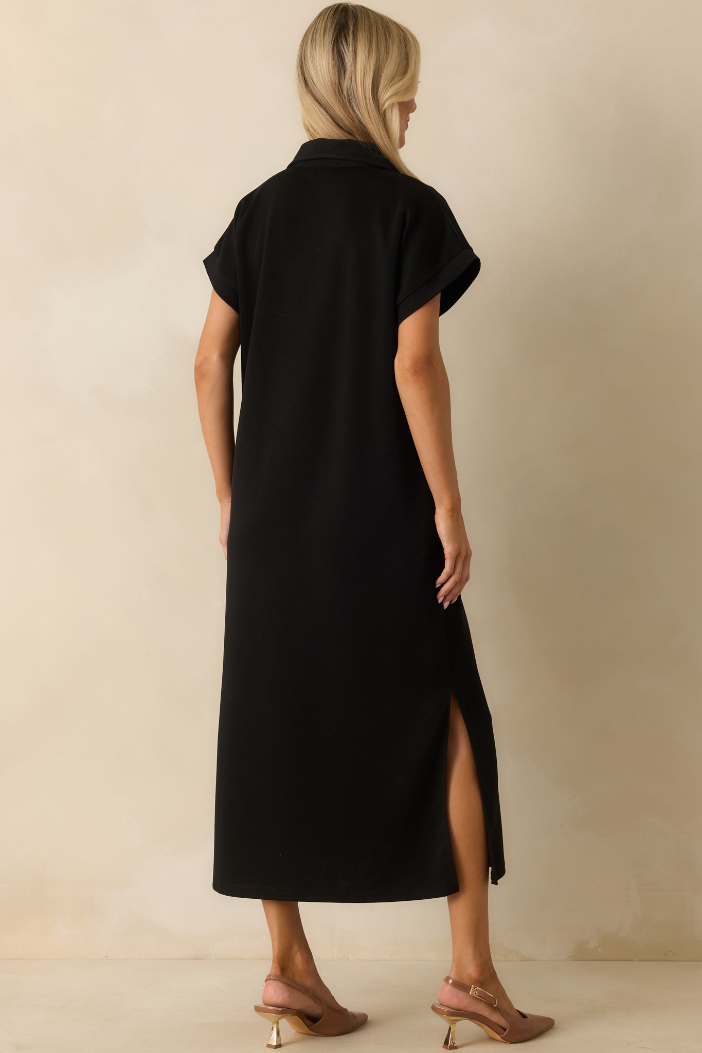 Rear view of the black midi dress with a relaxed fit and side slit detail.