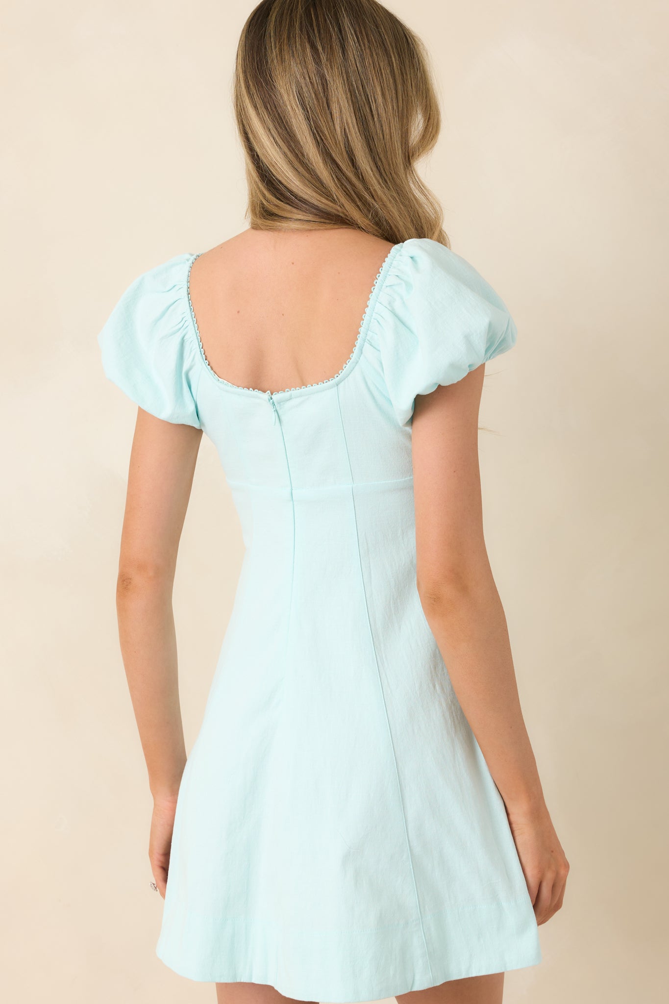 Rear view of aqua blue cotton mini dress with puff sleeves and flared skirt.