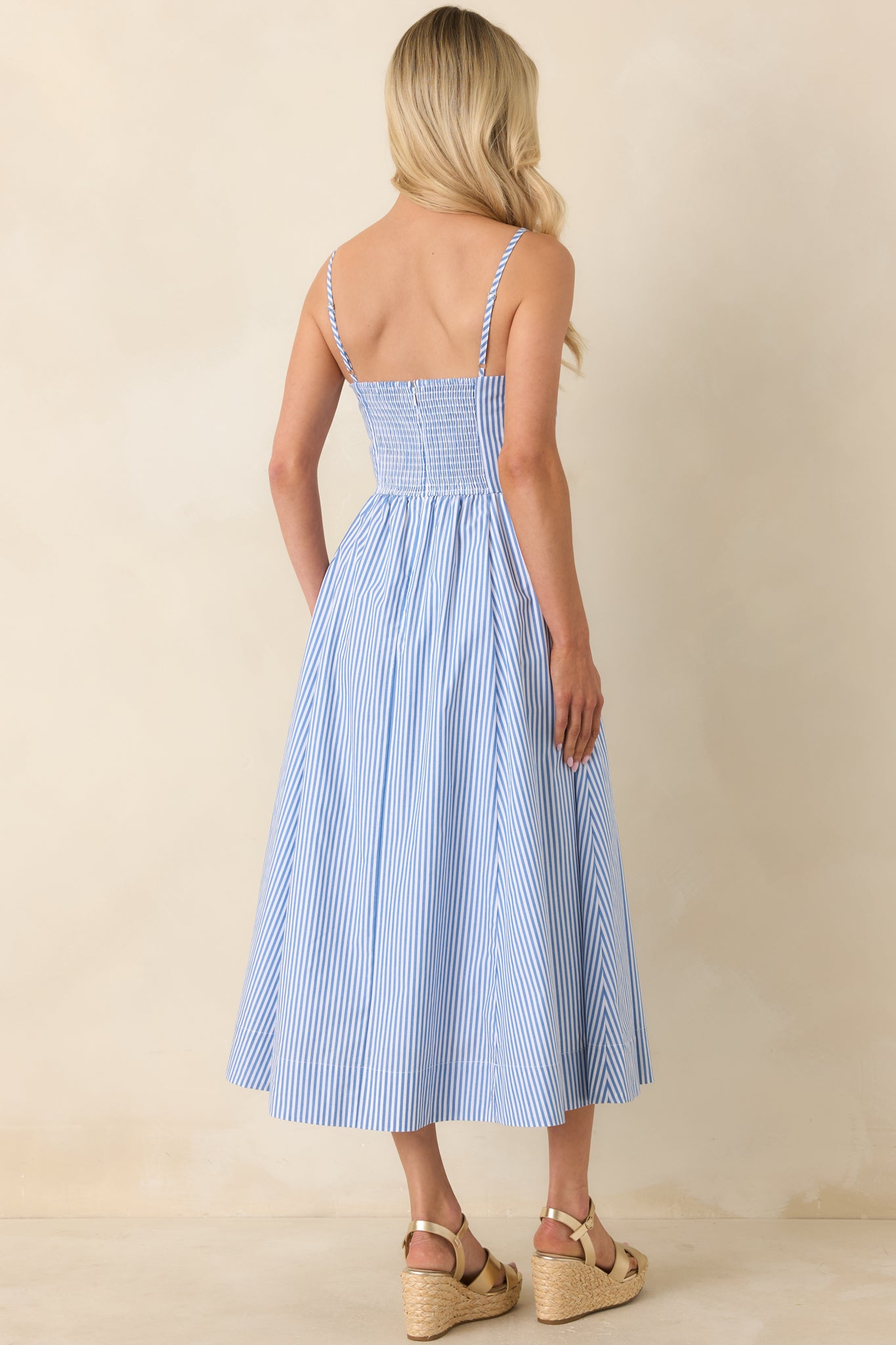 Rear view of blue striped midi dress with fitted bodice and flowing skirt.